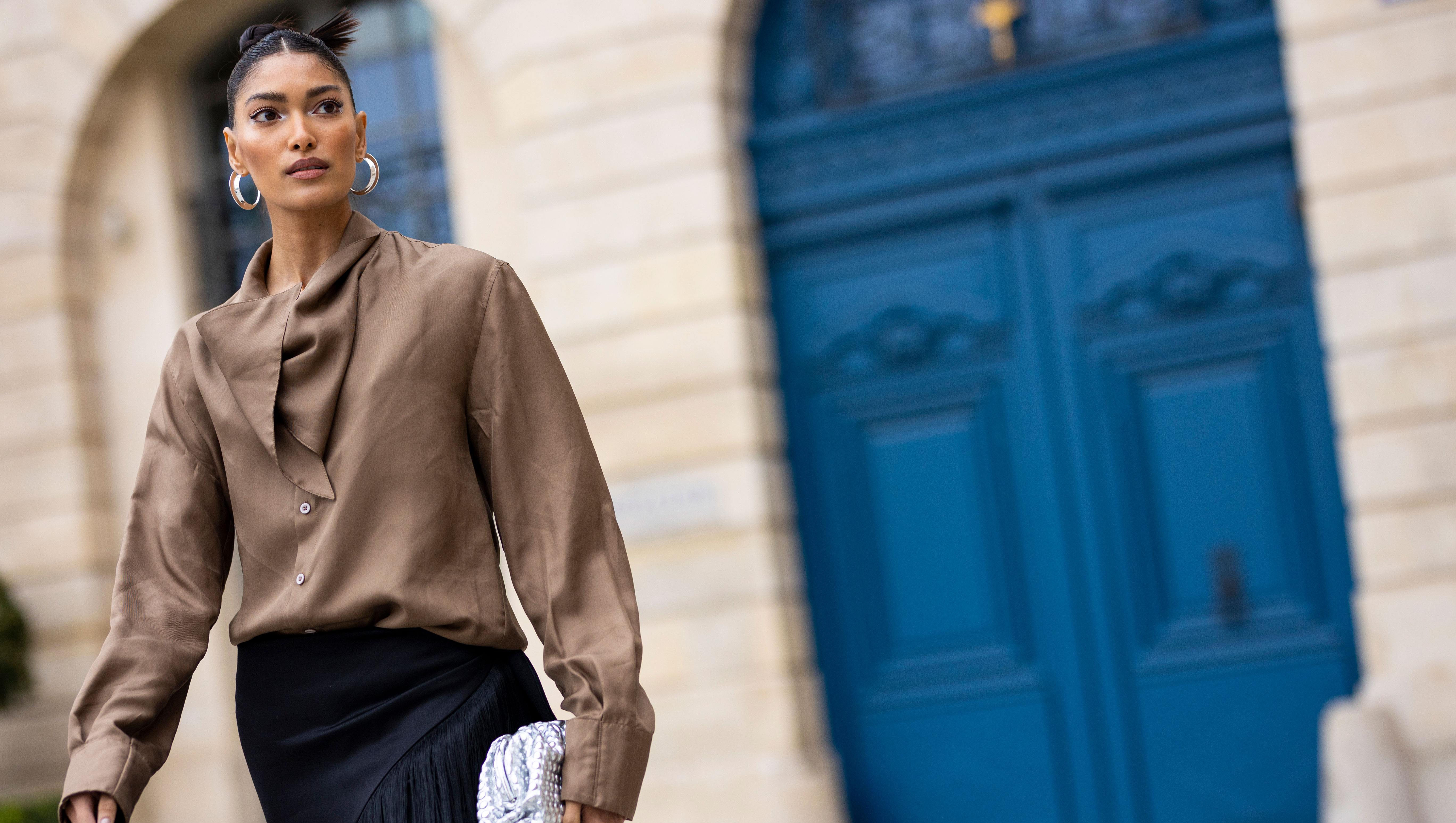 PARIS, FRANCE - MARCH 04: Pritika Swarup, wearing a brown blusa, white shoes and black fringes pants, is seen on the streets of Paris, during Paris Fashion Week - Womenswear F/W 2022-2023 on March 04, 2022 in Paris, France. (Photo by Claudio Lavenia/Getty Images)