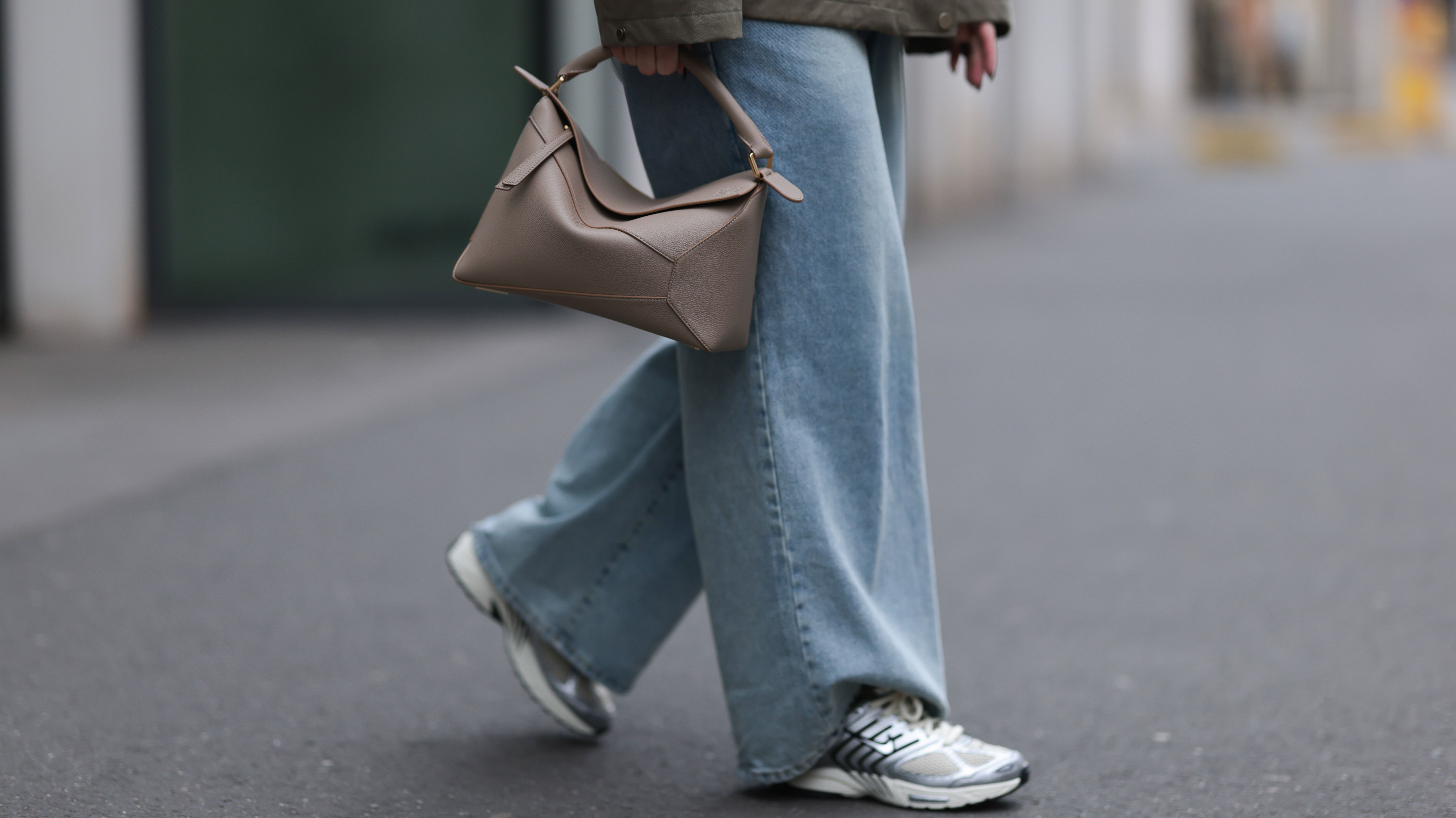 DUESSELDORF, GERMANY - MARCH 14: Maria Barteczko seen wearing g-lab olive green hooded waterproof parka jacket, The Frankie Shop blue denim used baggy jeans, LOEWE beige leather big Puzzle bag and Nike⁠ light khaki Pegasus sneaker with metallic details, on March 14, 2025 in Duesseldorf, Germany. (Photo by Jeremy Moeller/Getty Images)