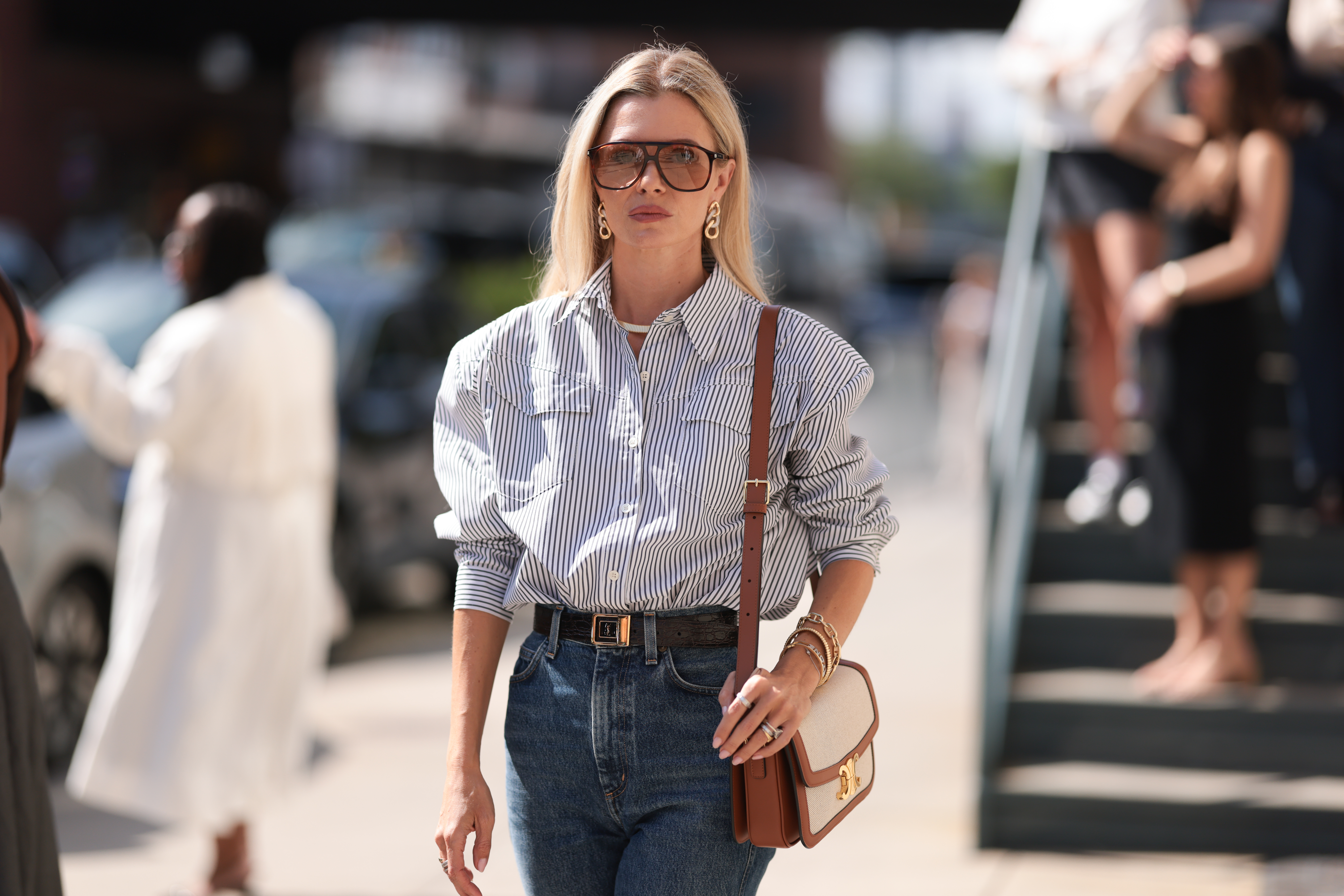 Fashion Week Guest seen wearing a white and darkblue blouse, denim blue jeans, black heels, white and brown Celine handbag, sunglasses and a black YSL belt outside Brandon Maxwell show during New York Fashion Week on September 06, 2024 in New York City.