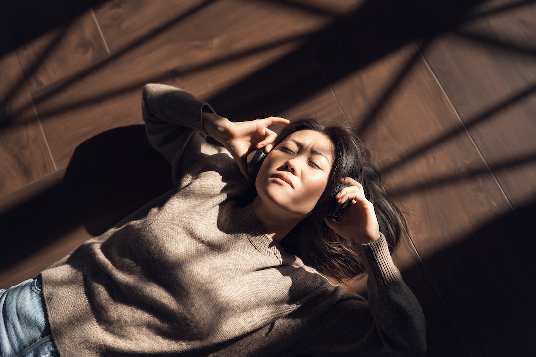 Woman in a brown sweater listening to music