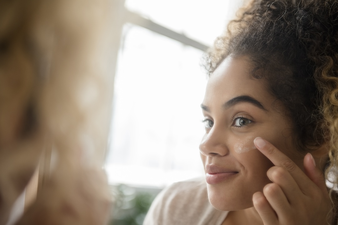 Woman applying lotion to her face