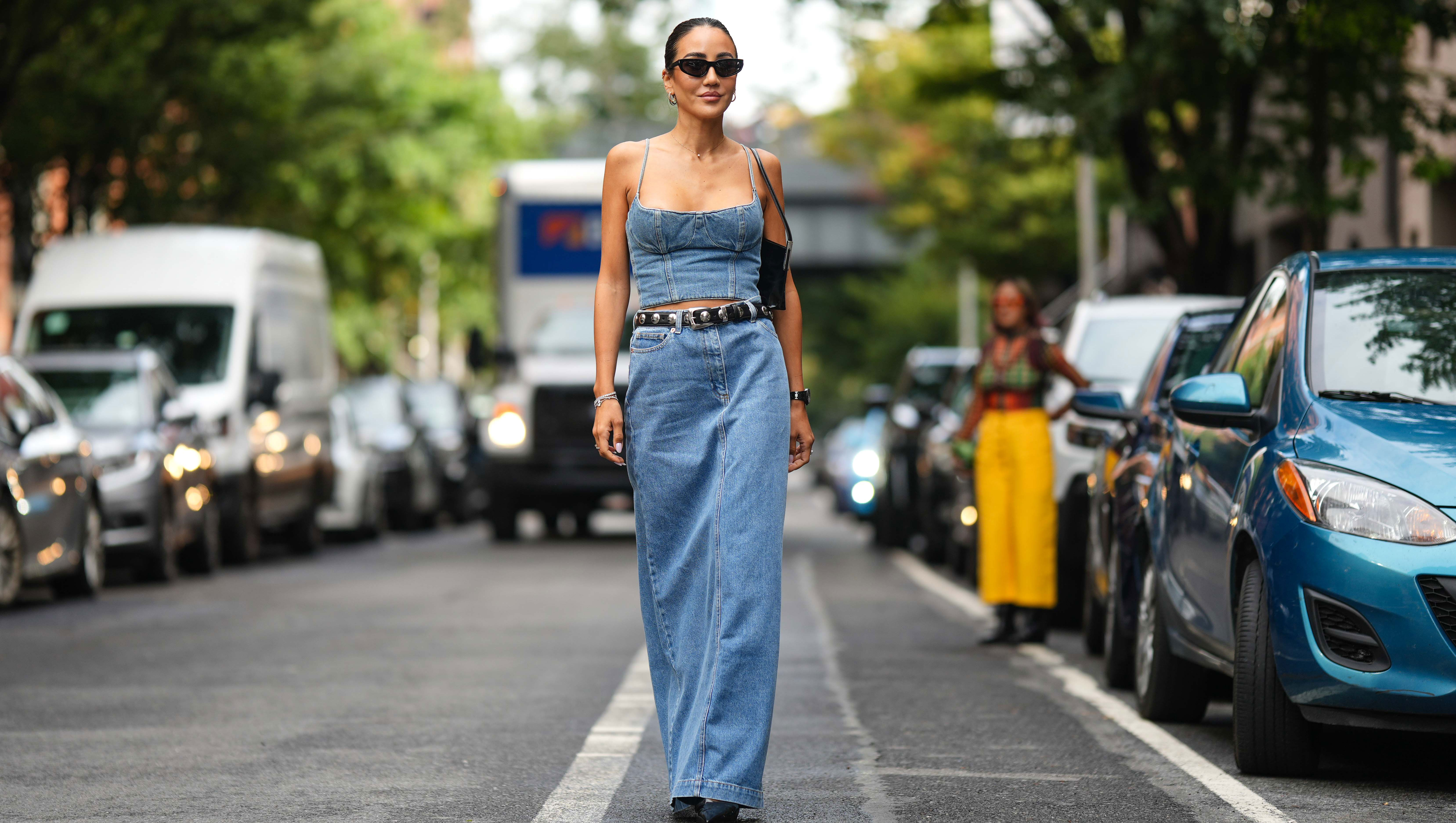 NEW YORK, NEW YORK - SEPTEMBER 10: Tamara Kalinic wears sunglasses, a blue denim off-shoulder low neck cropped top, a black leather studded belt, a blue denim maxi skirt, a black leather bag, outside Adeam, during New York Fashion Week, on September 10, 2023 in New York City. (Photo by Edward Berthelot/Getty Images)