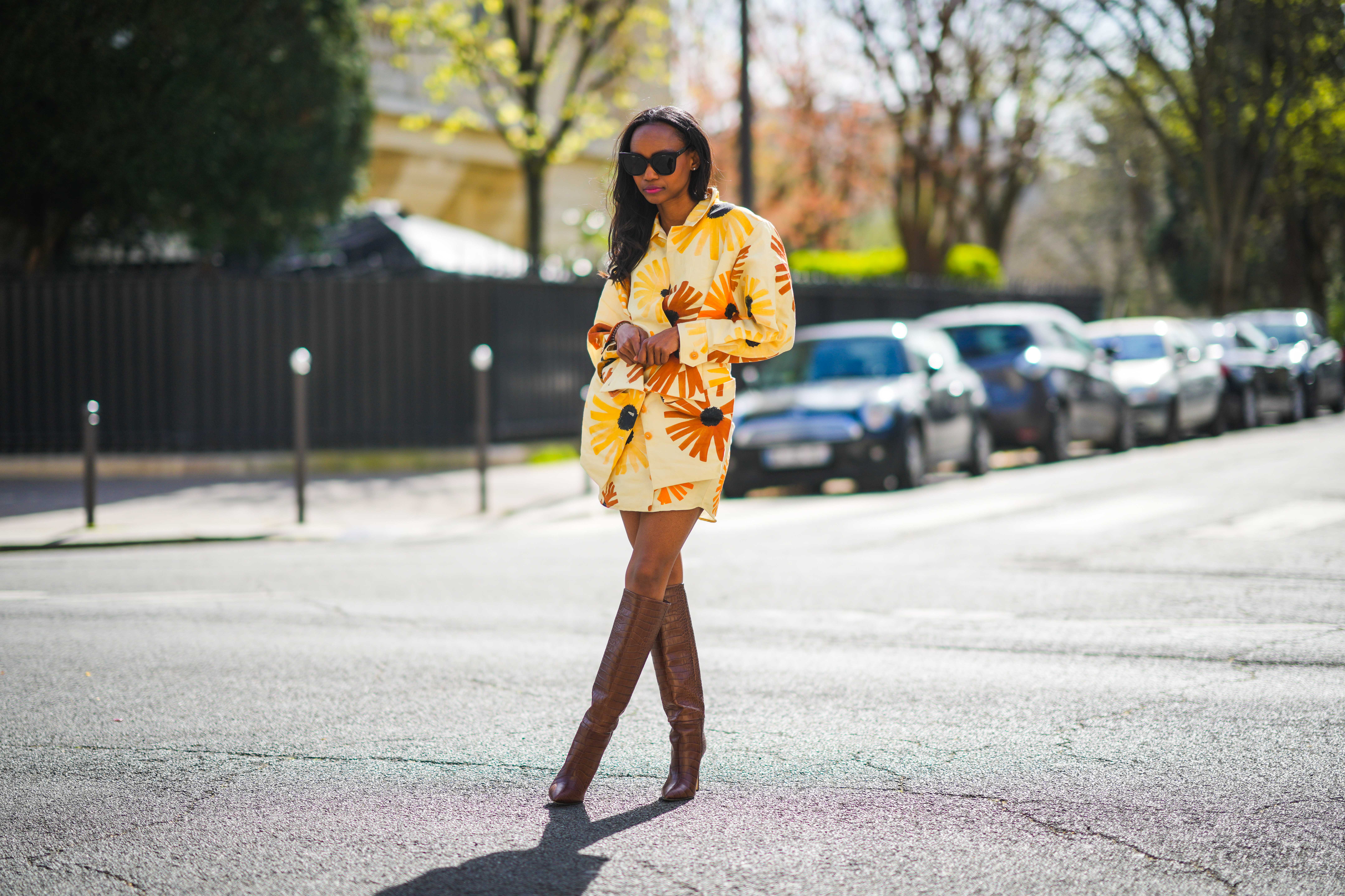 Emilie Joseph @in_fashionwetrust wears a yellow and orange floral print Jacquemus Murano dress with flap pockets and buttoned waist, Boots with Croc-effect leather knee-high boots from Paris Texas, on March 28, 2021 in Paris, France.
