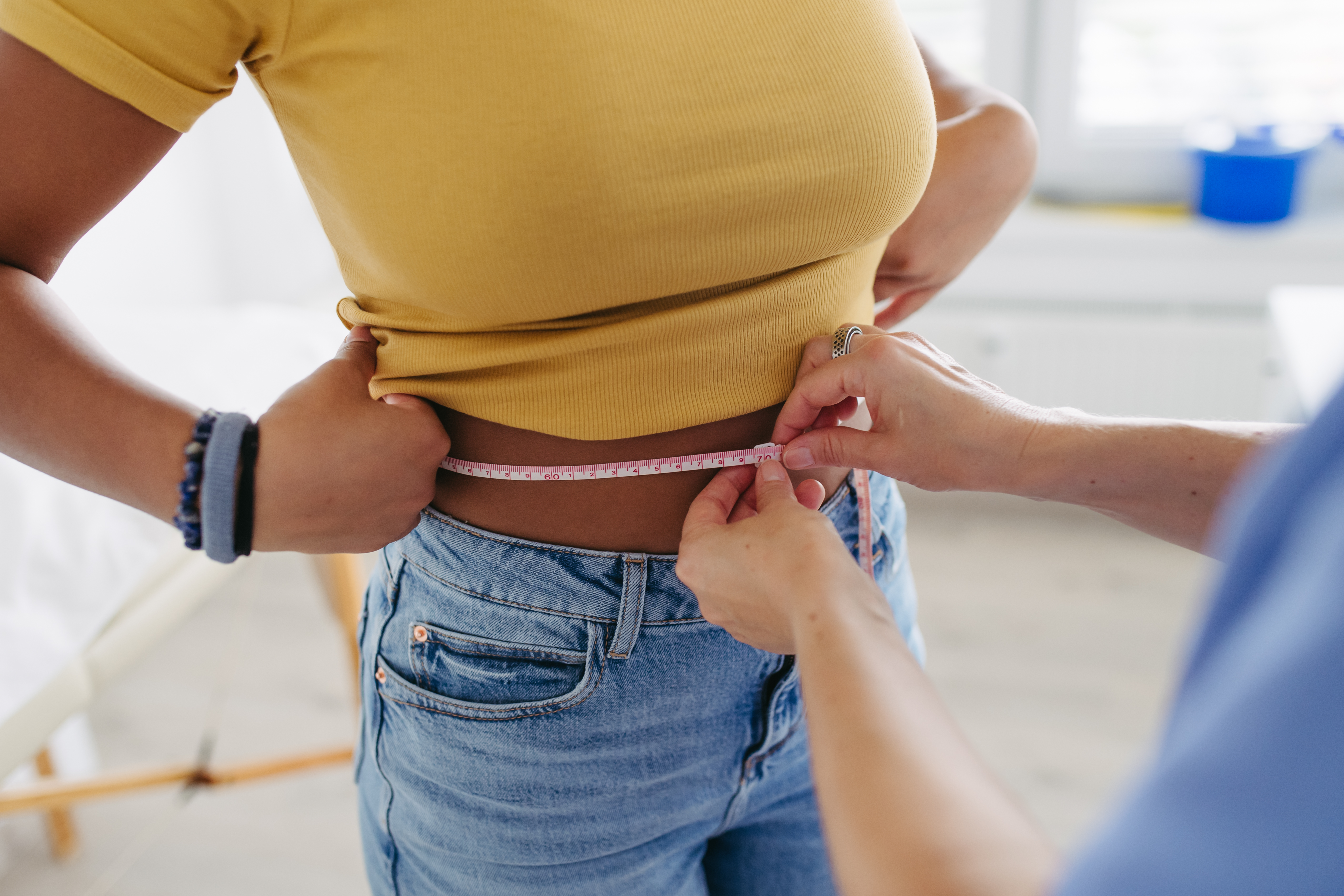 Diabetologist doctor measuring patient’s waist, examine abdominal obesity in diabetes clinic. Patient diagnosed with diabetes.
