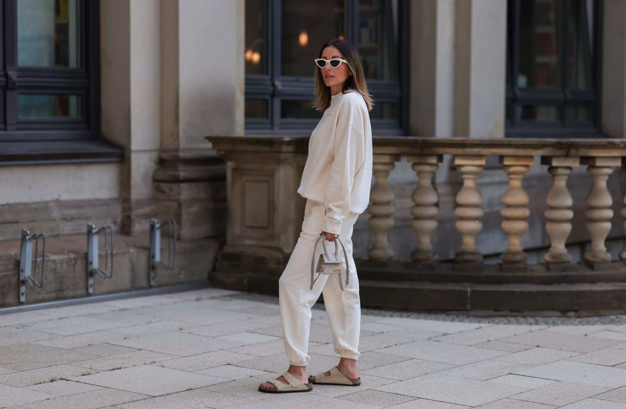 HAMBURG, GERMANY - AUGUST 16: Elise Seitz seen wearing white sunglasses from Celine, a creme white SohoStudios sweater, a creme white SohoStudios jogger pants, creme white linen Jacquemus Chiquito bag and beige suede Birkenstock Arizona sandals, on August 16, 2022 in Hamburg, Germany. (Photo by Jeremy Moeller/Getty Images)