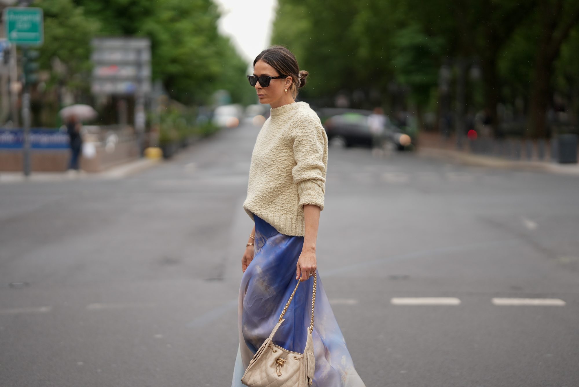 DUSSELDORF, GERMANY - MAY 27: Patricia Wirschke is seen wearing a blue printed silk-organza maxi skirt from Zimmermann, a cream white wool knit sweater with straight fit and round neckline from Jil Sander, brown cat-eye sunglasses with tortoiseshell finish from Celine, a beige small calfskin Chanel 25 hobo handbag with golden hardware and chain and logo details from Chanel, yellow golden Serpenti Viper hoop earrings with snake-like design from Bvlgari, a golden Juste un Clou bracelet from Cartier, a yellow golden Serpenti Viper bracelet with snake-like design from Bvlgari, a yellow golden Love bracelet from Cartier, a silver diamond ring on May 27, 2025 in Dusseldorf, Germany. (Photo by Moritz Scholz/Getty Images)