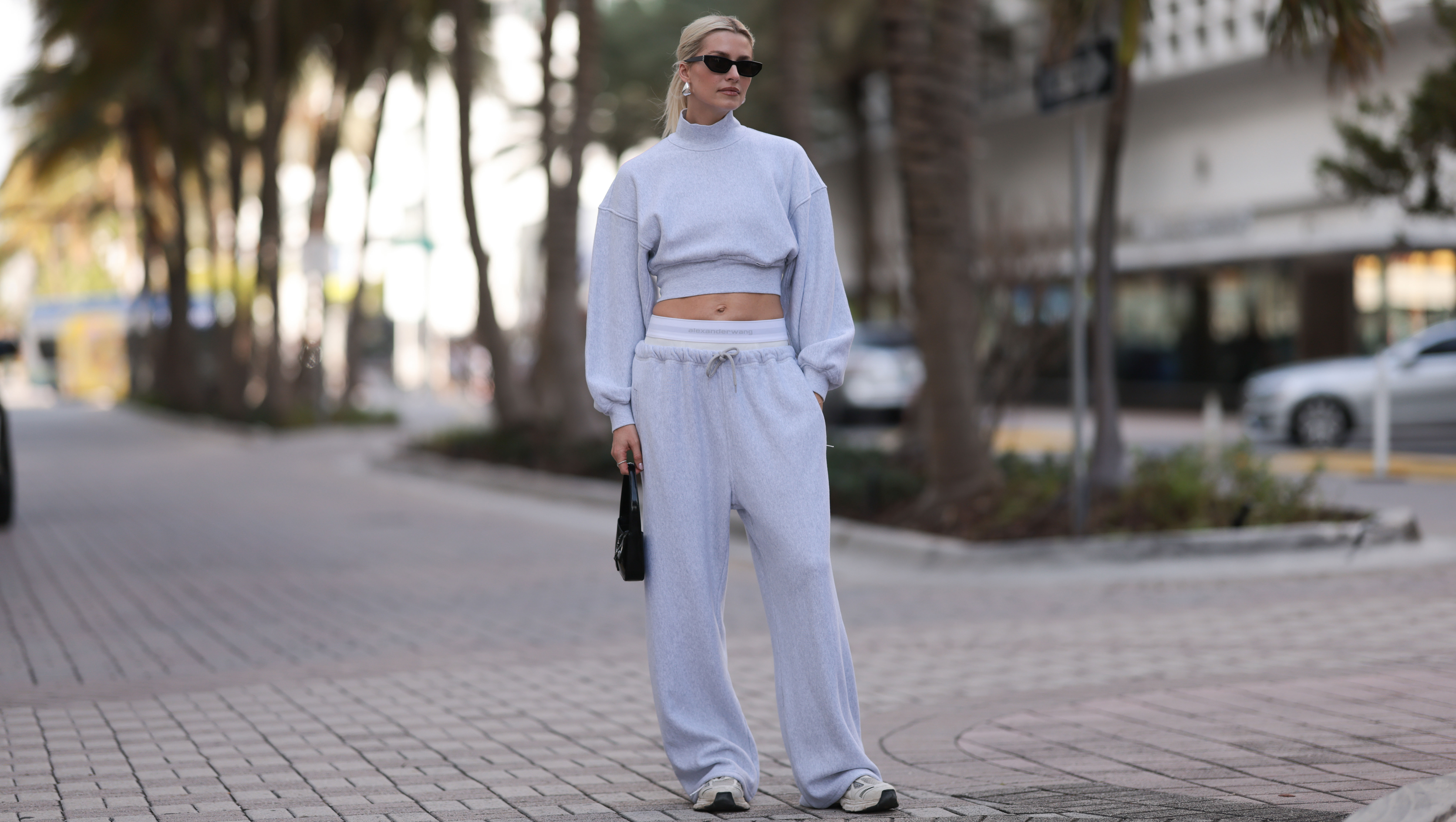 MIAMI, FLORIDA - DECEMBER 08: Lena Gercke seen wearing Saint Laurent black sunglasses, silver statement necklace, Alexander Wang light grey high neck cotton cropped jumper / sweater, Alexander Wang light grey cotton wide leg jogger pants with underwear detail, Saint Laurent black varnishes leather mini bag and Axel Arigato white leather sneakers, on December 08, 2023 in Miami, Florida. (Photo by Jeremy Moeller/Getty Images)2