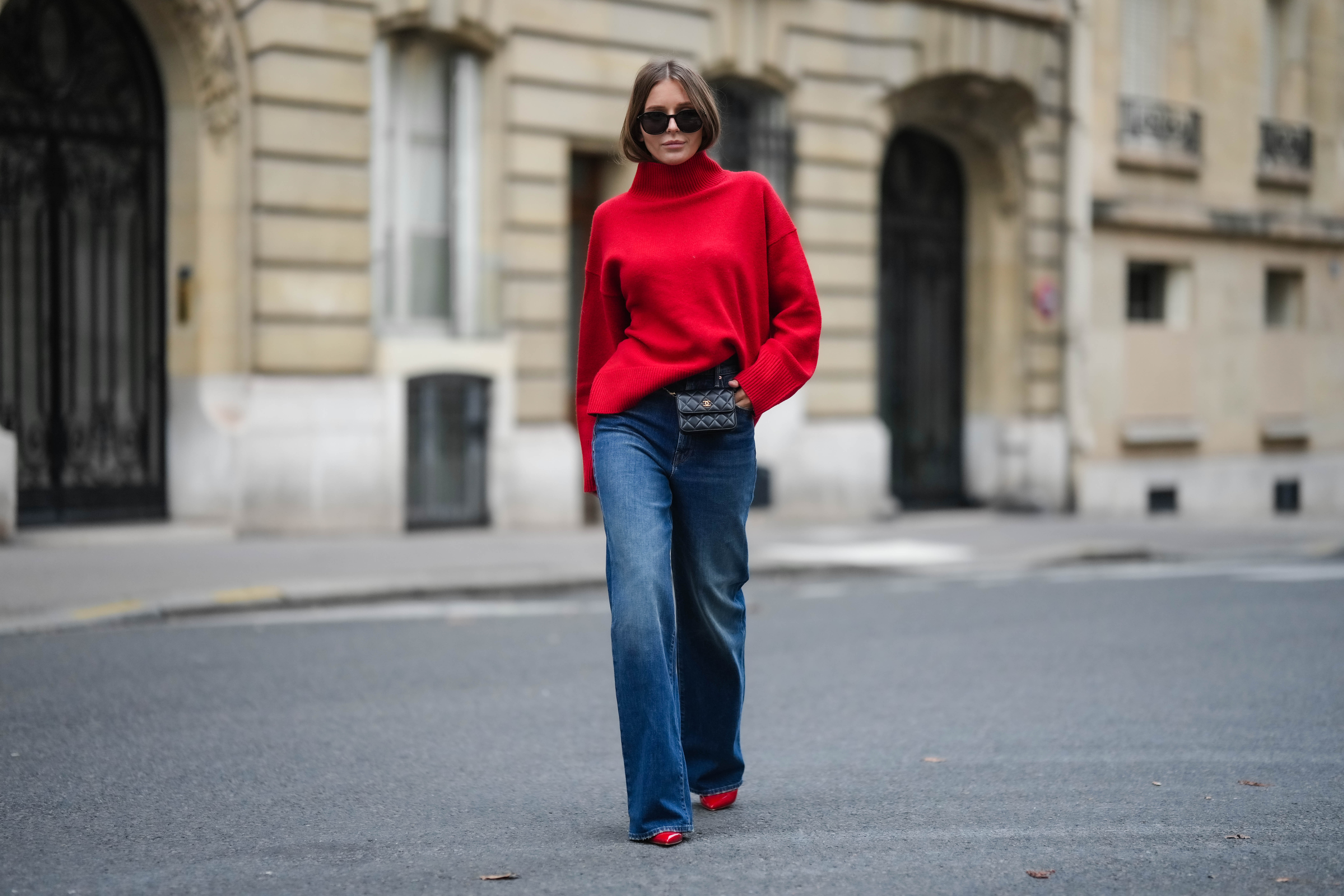 PARIS, FRANCE - NOVEMBER 10: Diane Batoukina wears black sunglasses, a red wool ribbed turtleneck pullover, a black shiny leather belt bag from Chanel, blue faded denim wide legs pants, red shiny varnished leather pointed pumps heels shoes, during a street style fashion photo session, on November 10, 2022 in Paris, France. (Photo by Edward Berthelot/Getty Images)