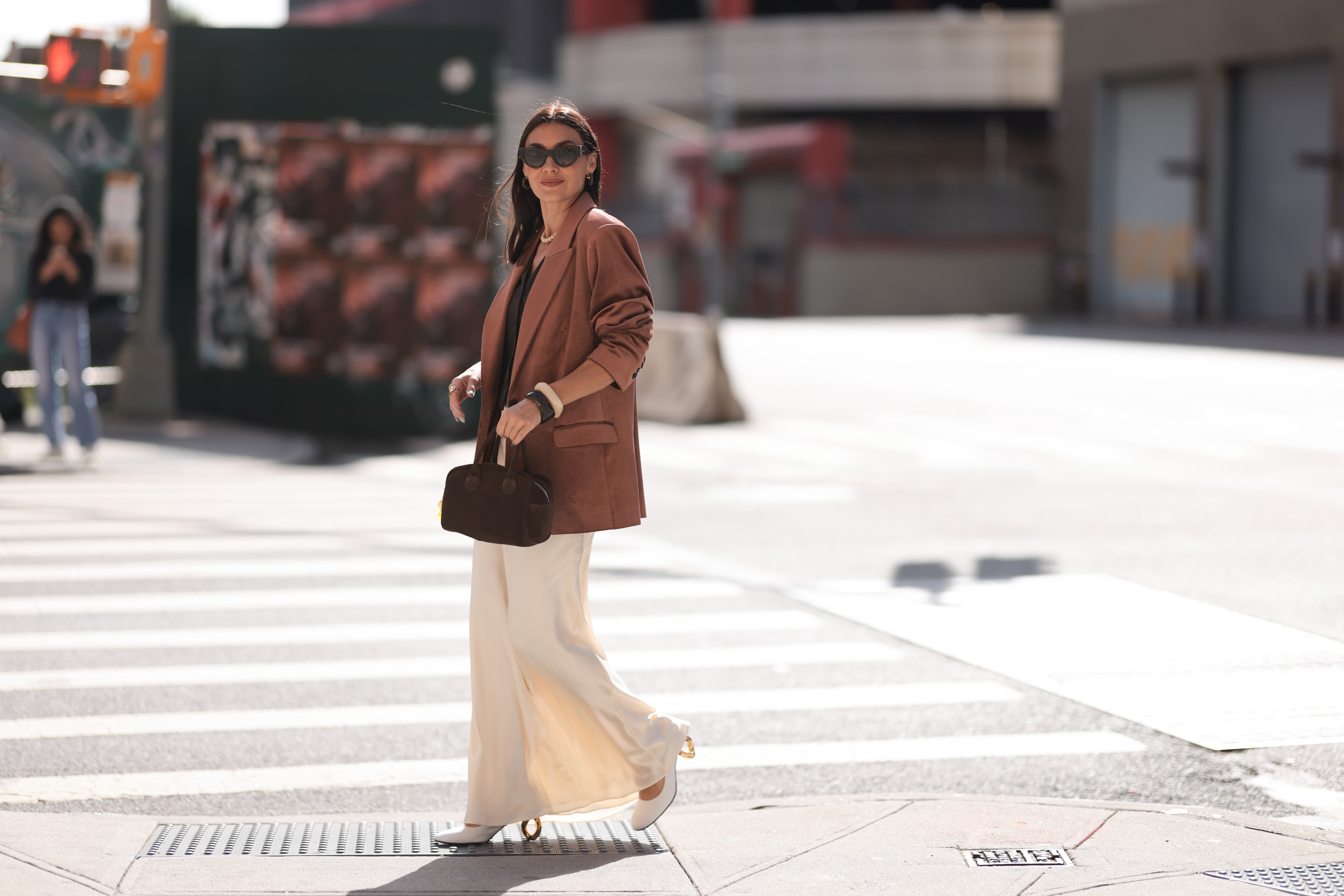 NEW YORK, NEW YORK - SEPTEMBER 08: Yana Echko seen wearing YSL brown sunglasses, Bottega Veneta brown leather earrings, white pearl necklace, The Frankie Shop brown pinstripe vest, Express light brown corduroy blazer jacket, Reformation cream white maxi silk long skirt, MARGE SHERWOOD brown suede leather small bag, Kenneth Jay Lane gold ring, cream white / brown bangle and JW Anderson white leather pumps, outside the Bach Mai show, during the New York Fashion Week, on September 08, 2024 in New York City. (Photo by Jeremy Moeller/Getty Images)