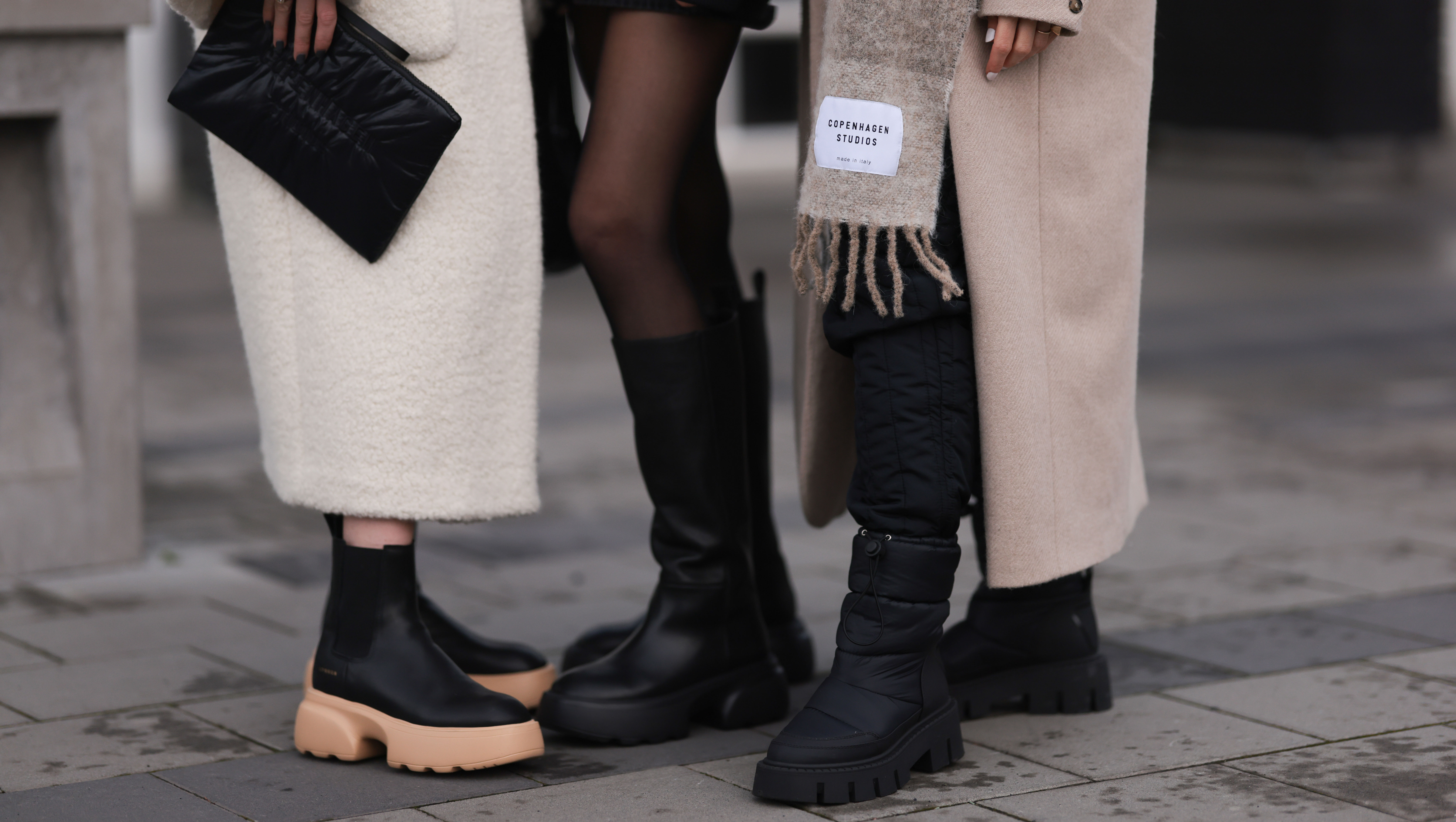 REYKJAVIK, ICELAND - NOVEMBER 15: Annabel Rosendahl (L) is seen wearing Copenhagen Studios CPH 276 Vitello black/ pale beige boots, Copenhagen Studios black clutch bag and Dorothee Schumacher creme white wool coat; Marie Hindkaer (M) is seen wearing a black Prada nylon bag, black leather Copenhagen Studios CPH145 boots, creme white Samsoe Samsoe knit sweater, Acne Studios black short skirt and a black Jw Anderson x Uniqlo jacket; Mie Juel (R) wears Copenhagen Studios beige wool scarf, Copenhagen Studios CPH149 black boots, Birgitte Herskind beige wool coat and black Basic Apparel pants, on November 15, 2022 in Reykjavik, Iceland. (Photo by Jeremy Moeller/Getty Images for Copenhagen Studios)