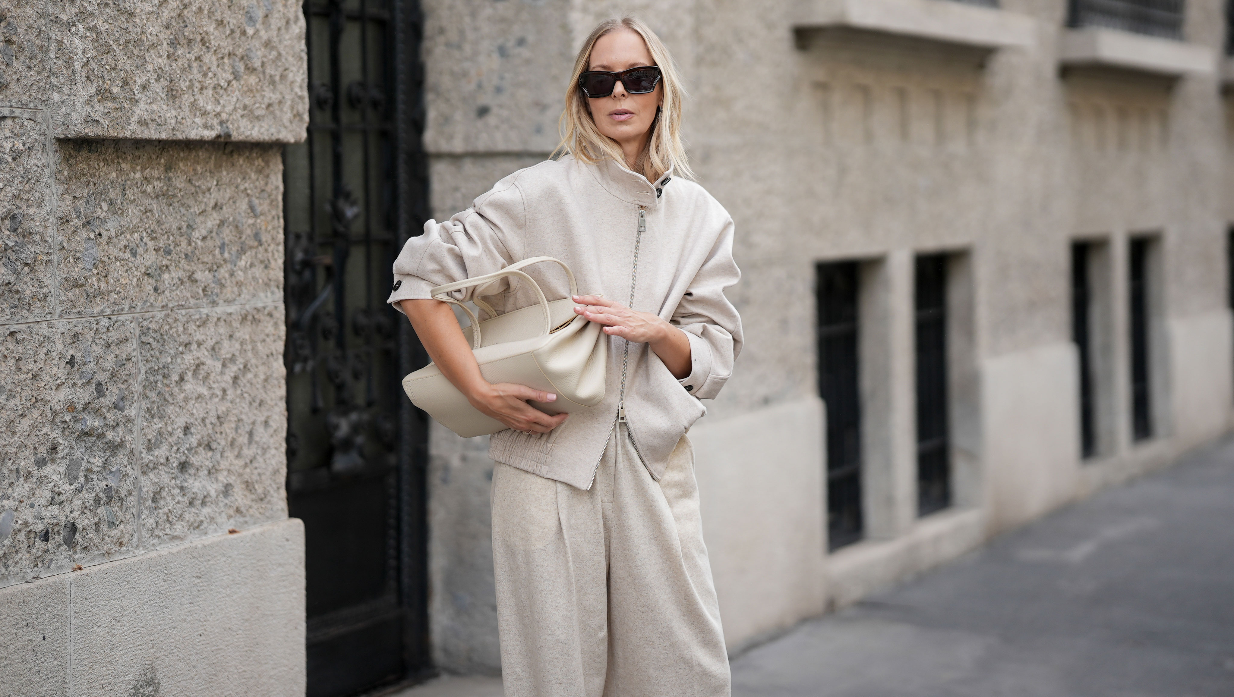 MILAN, ITALY - SEPTEMBER 25: Mirja Klein is seen wearing a beige wool zip-up bomber jacket with a high collar and elastic waistband by Liviana Conti; beige wide-leg wool trousers in a relaxed silhouette by Liviana Conti; an off-white structured leather handbag with top handles and a flap top by Liviana Conti; rectangular black sunglasses with a glossy acetate frame by Loewe; her blond hair is worn loose with a middle parting on September 25, 2025 in Milan, Italy. (Photo by Moritz Scholz/Getty Images)