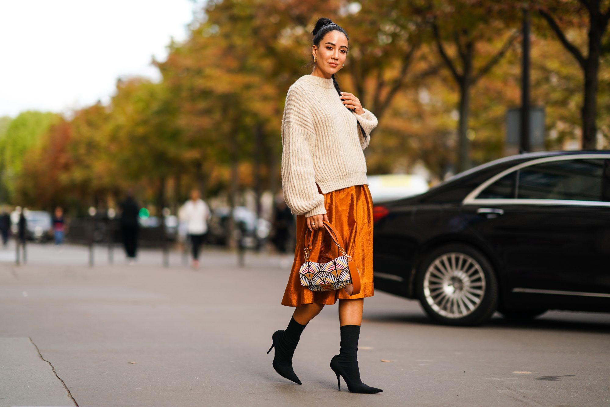 PARIS, FRANCE - SEPTEMBER 28: Tamara Kalinic wears a wool pullover, an orange shiny silky skirt, earrings, a Fendi bag, black high heeled boots, outside CDG Comme des Garçons, during Paris Fashion Week - Womenswear Spring Summer 2020 on September 28, 2019 in Paris, France. (Photo by Edward Berthelot/Getty Images)
