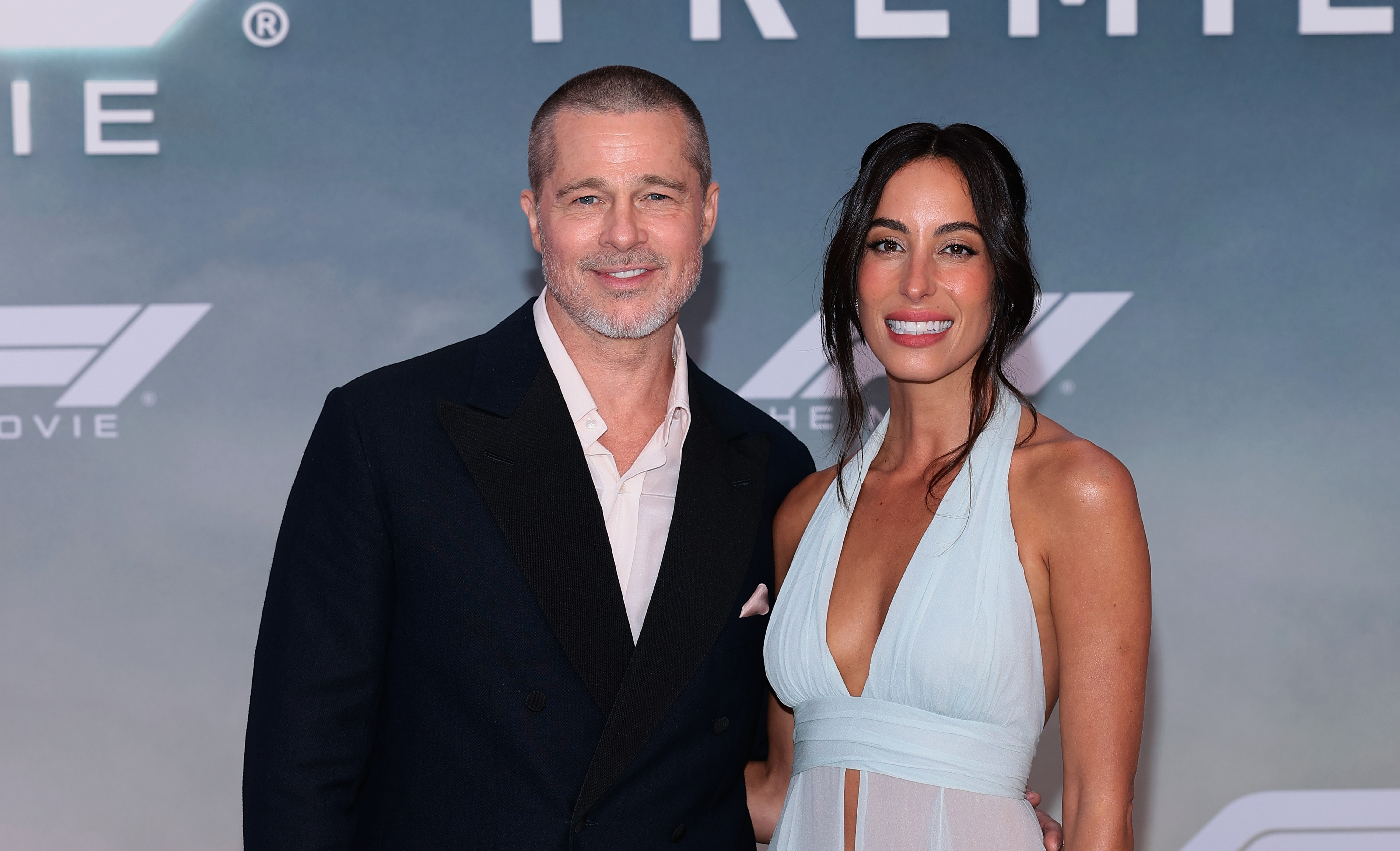 Brad Pitt and Ines de Ramon smiling together on the "F1" premiere red carpet.