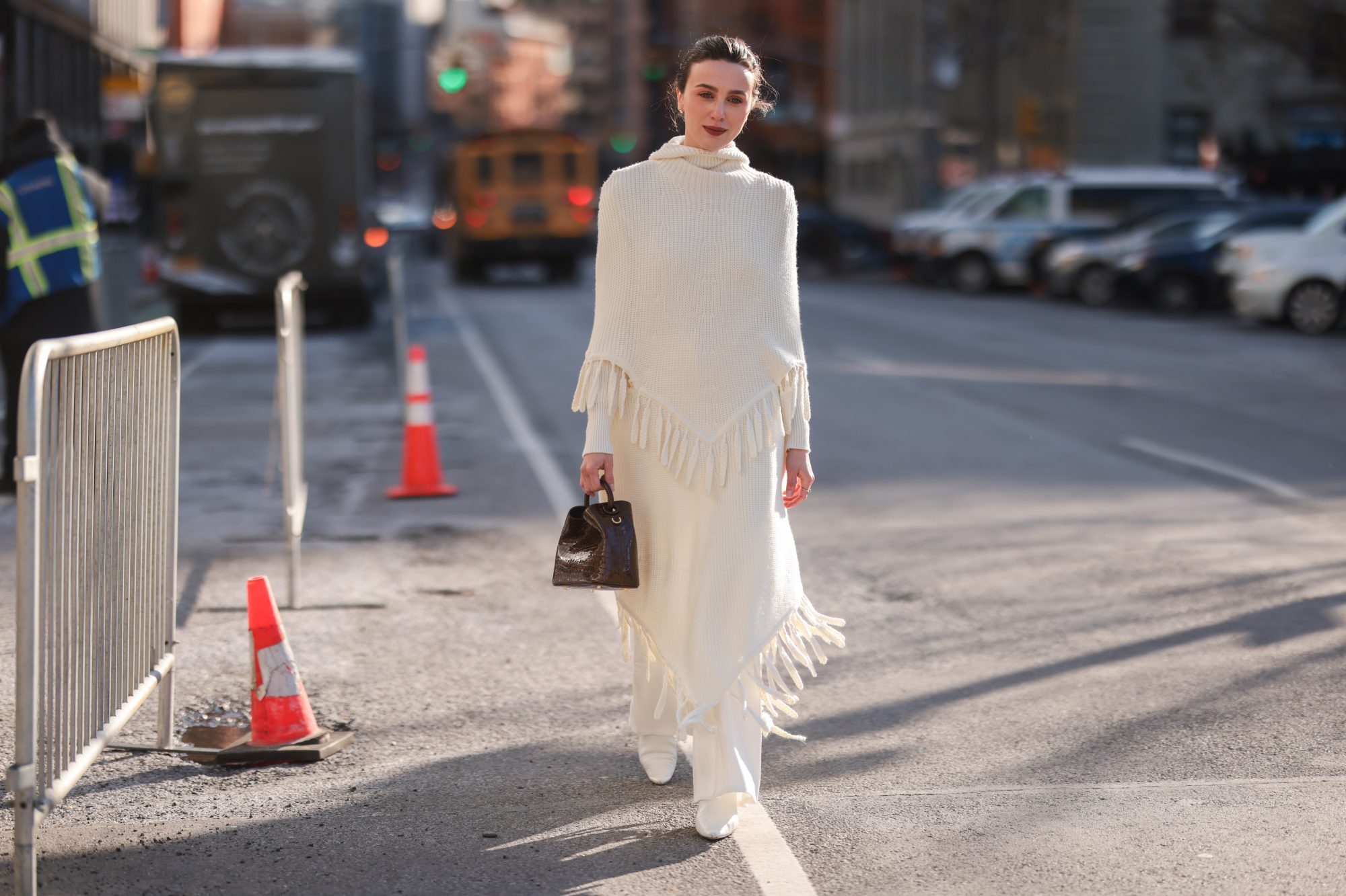 NEW YORK, NEW YORK - FEBRUARY 14: Mary Leest wears gold earrings, a white ribbed wool high neck fringed cloak, a matching white fringed wool skirt, a dark brown shiny leather crocodile print pattern handbag, silver rings outside the Bevza show , during New York Fashion Week, on February 14, 2022 in New York City. (Photo by Jeremy Moeller/Getty Images)
