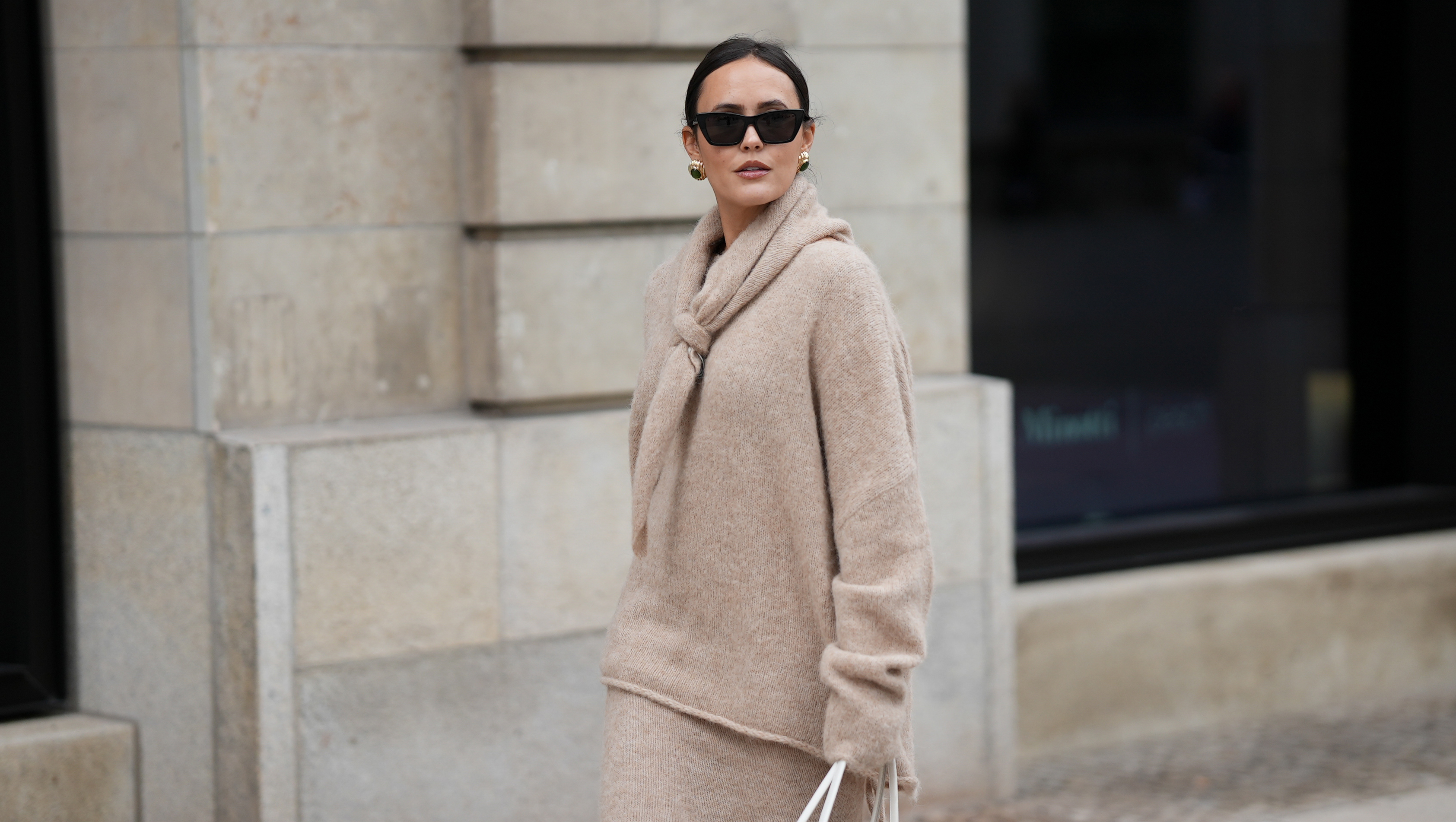 HAMBURG, GERMANY - OCTOBER 16: Laura Noltemeyer is seen wearing an oversized beige alpaca wool sweater with tie-back detailing by Aylin K√∂nig; a long alpaca wool knit skirt in a straight cut by Aylin K√∂nig; an alpaca knit scarf draped and knotted around the neck by Aylin K√∂nig; a white intrecciato leather handbag called ‚ÄûArco Bag‚Äú by Bottega Veneta; slim black cat-eye sunglasses by Yves Saint Laurent; gold statement earrings with a green stone detail by Mango; her brown and straight hair is tied in a low ponytail on October 16, 2025 in Hamburg, Germany. (Photo by Moritz Scholz/Getty Images)