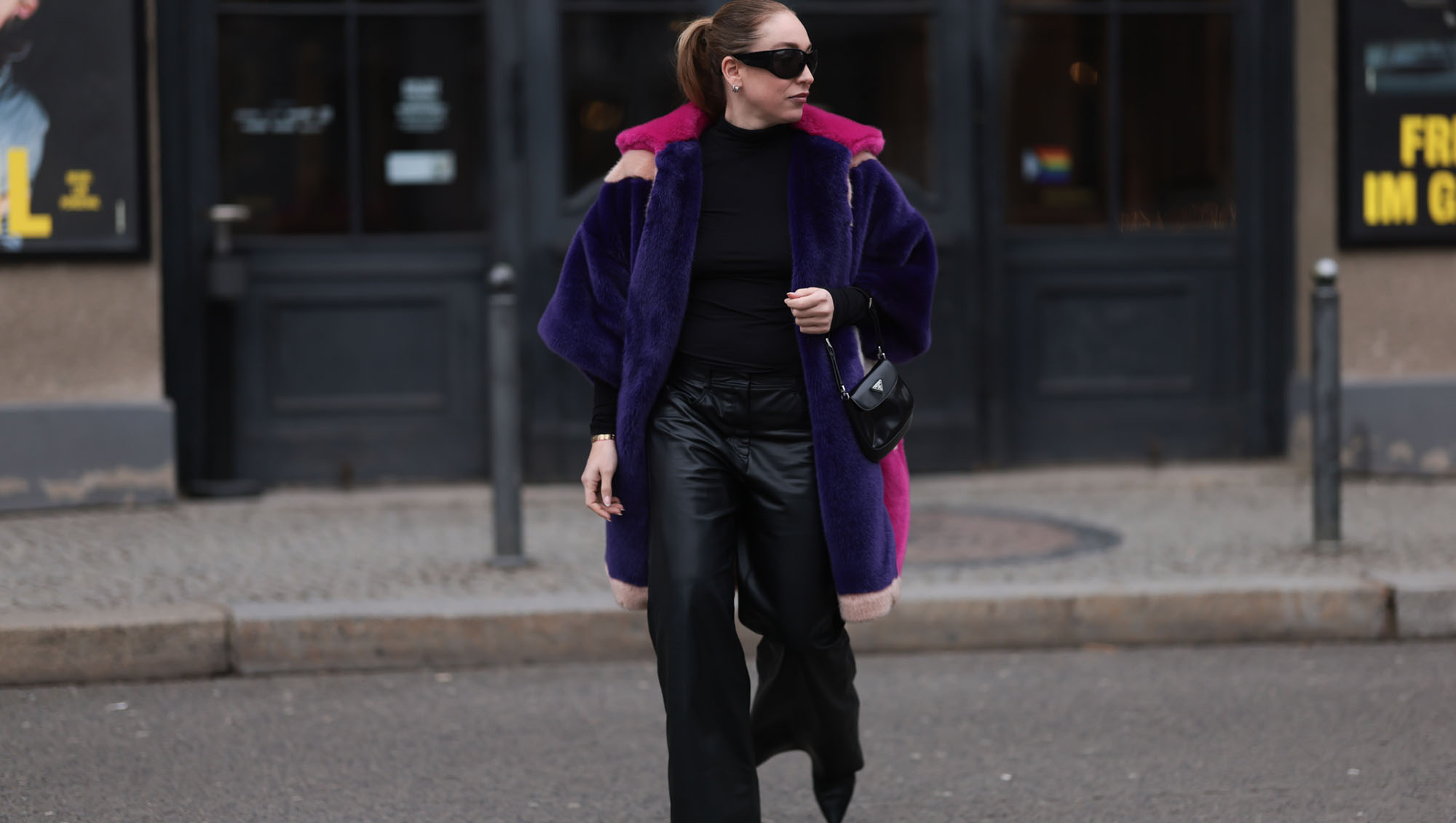 BERLIN, GERMANY - FEBRUARY 08: Sonia Lyson seen wearing & Other Stories black sunglasses, silver earrings, black wool knit high neck sweater, Marina Hoermanseder pink, purple, white, beige fake fur hooded short coat, Marc Cain black leather wide leg pants, Prada Cleo black leather mini bag and Jimmy Choo leather heeled boots, on February 08, 2024 in Berlin, Germany.