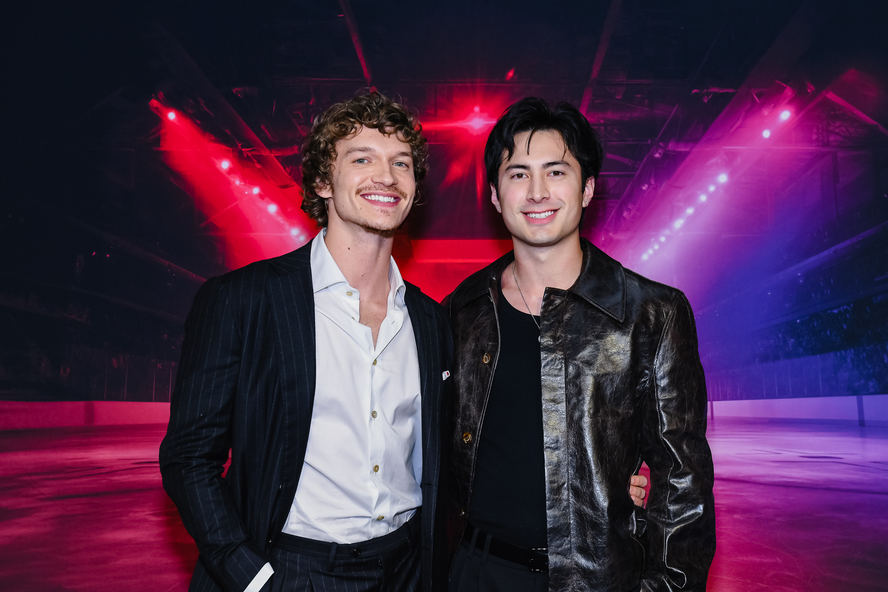 Connor Storrie and Hudson Williams smiling together at the "Heated Rivalry" season 1 premiere in Toronto.