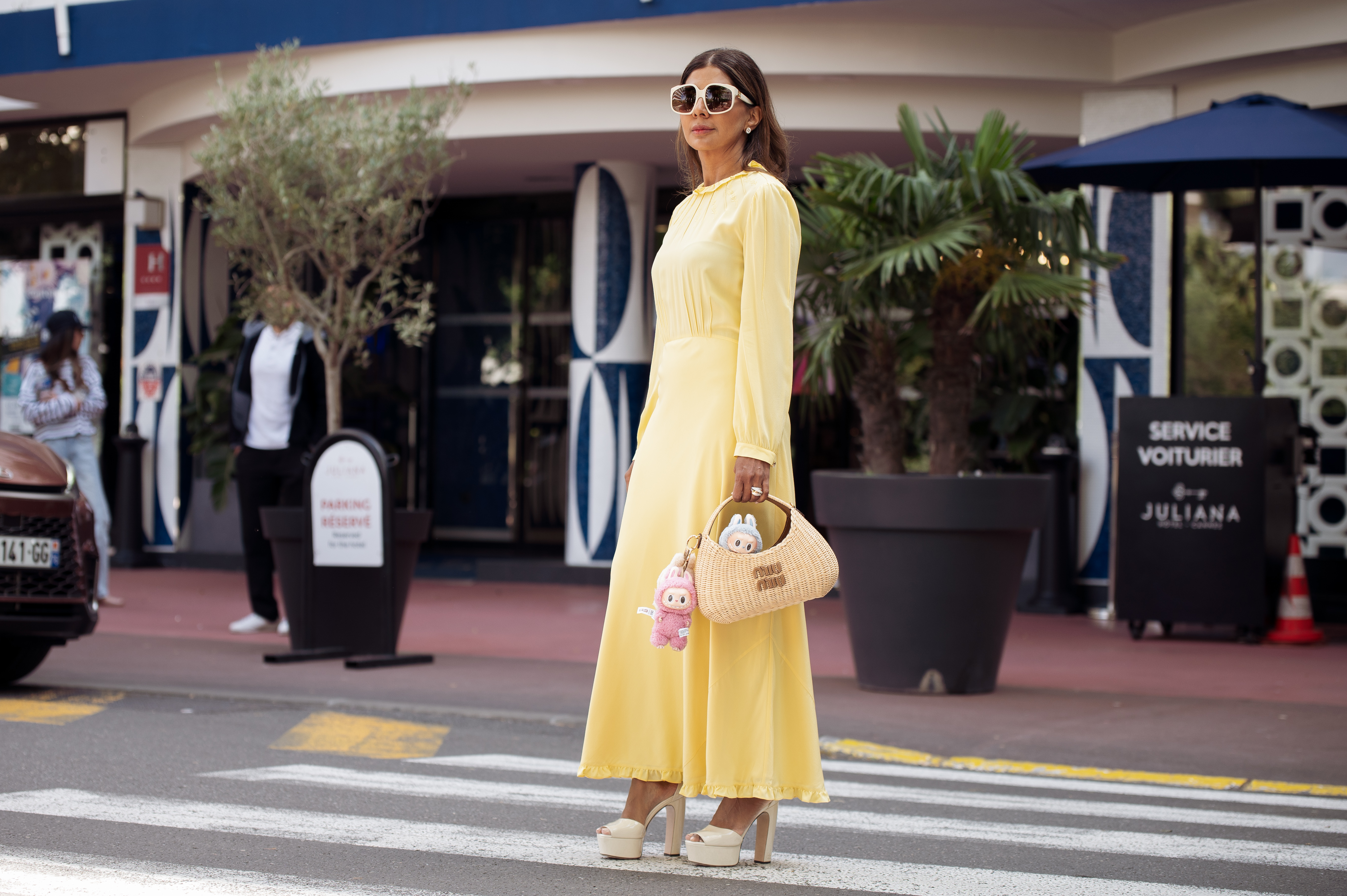 CANNES, FRANCE - MAY 17: Zufi Alexander wears an all Miu Miu look made of butter yellow long summer dress, off white pumps high heels with platform, sunglasses and straw Miu Miu bag with attached Labubu bag charms during day five of the 78th Cannes Film Festival on May 17, 2025 in Cannes, France. (Photo by Raimonda Kulikauskiene/Getty Images)