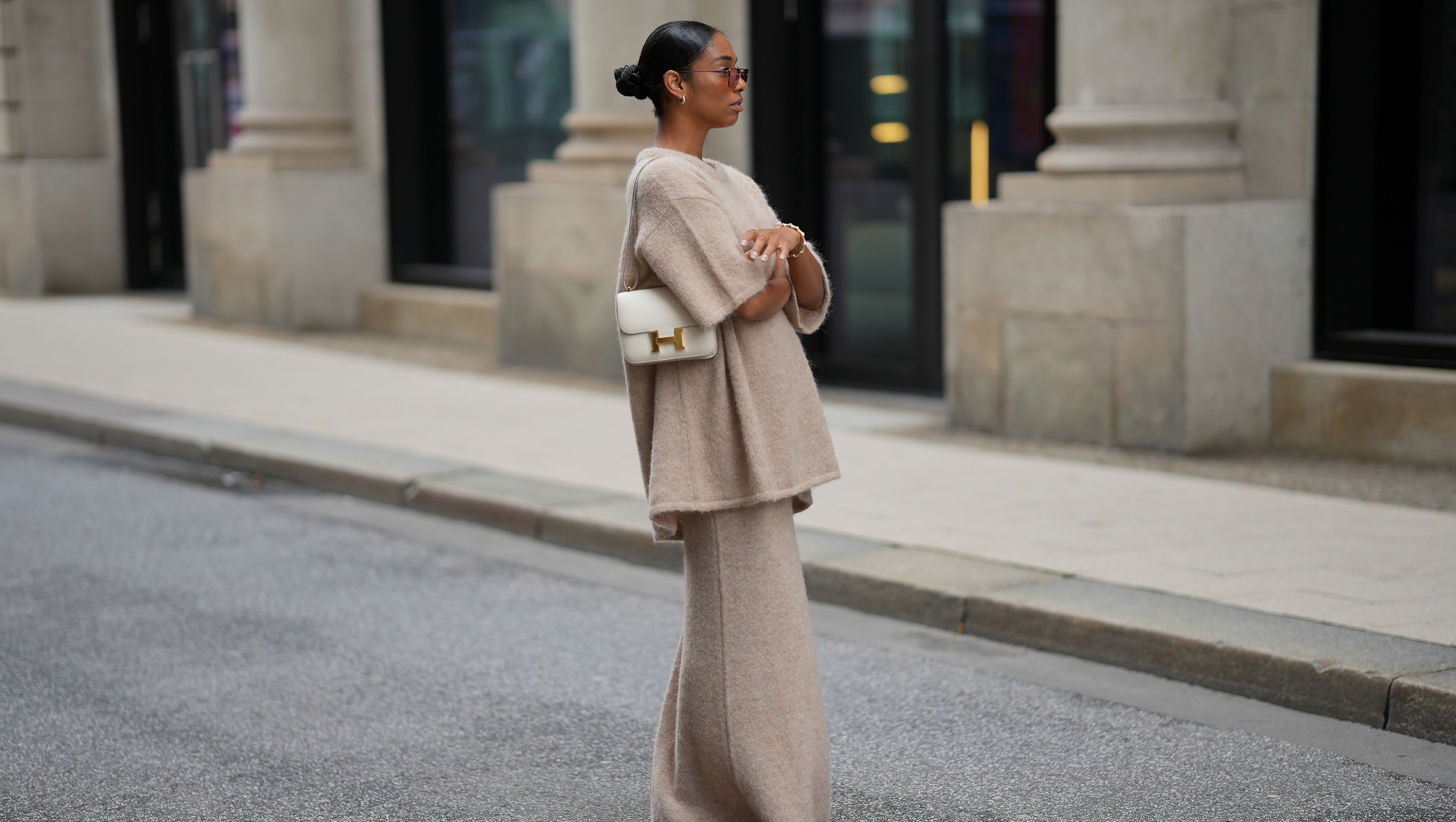 HAMBURG, GERMANY - SEPTEMBER 19: Cherifa Akili is seen wearing an oversized beige short-sleeve knit sweater with a soft texture from Byaylink√∂nig; a matching long knit skirt in a beige tone with subtle seaming at the hem from Byaylink√∂nig; red pointed-toe heels with a low cut from Prada; The Constance structured white leather shoulder bag with a gold clasp from Hermes; a gold spiral shaped bracelet from Elouise; two gold, metallic rings from Elouise, Wempe; lightly tinted sunglasses in a warm shade COS; her black hair is pulled back in a sleek bun on September 19, 2025 in Hamburg, Germany. (Photo by Moritz Scholz/Getty Images)