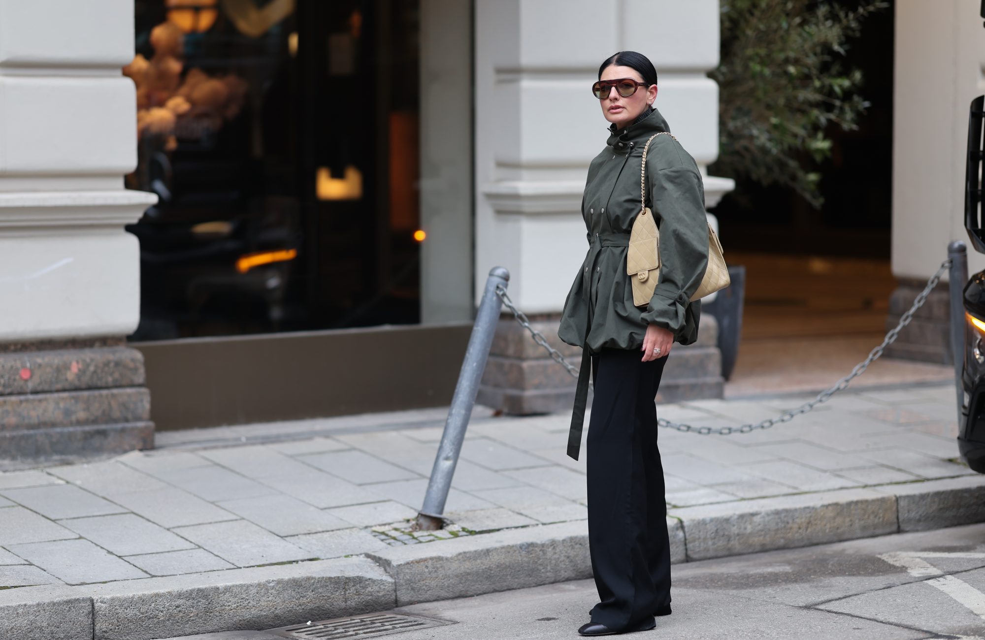 MUNICH, GERMANY - FEBRUARY 1: Sofiya Bogopolska Balci is seen wearing a calligraphy green jacket with a hip belt and buckles on the arms and balloon hems with silver buttons; dark grey wool jumper; straight-cut black fabric trousers from COS; black leather boots with rectangular toes from Ayede; dark brown aviator sunglasses from Prada, silver stud earrings from Cartier; gold and silver rings from Cartier; a silver Rolex; a pastel yellow Chanel 25 bag in caviar leather; her black hair is styled in sleek bun on February 1, 2026 in Munich, Germany. (Photo by Moritz Scholz/Getty Images)