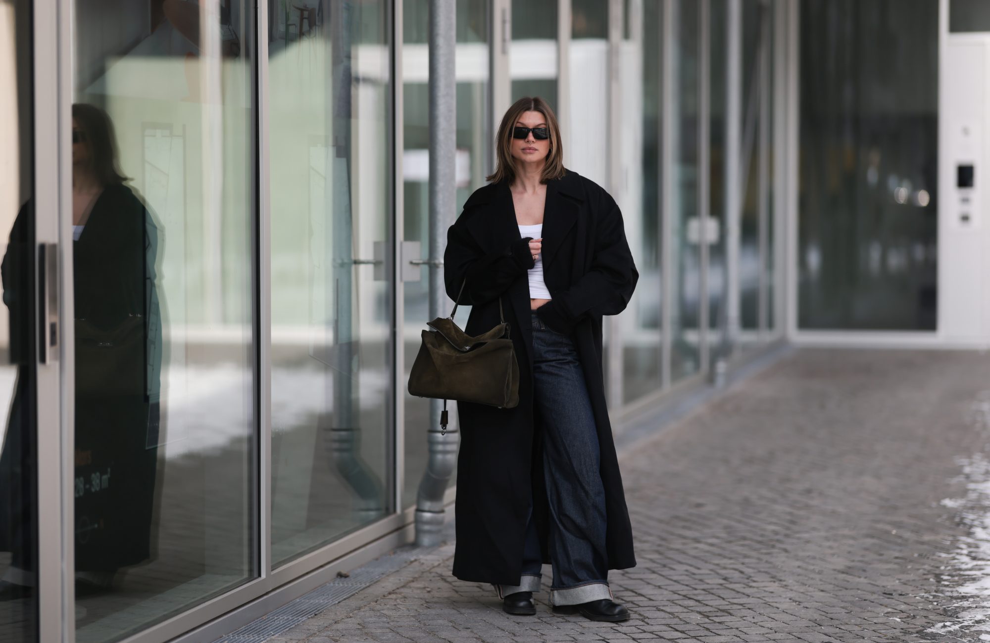 BERLIN, GERMANY - FEBRUARY 19: Sophia Geiss is seen wearing an oversized Bondi black coat layered over a fitted Black Palms top, styled with Acne Studios jeans in a relaxed, straight-leg silhouette. She completes the look with Alohas shoes, adding a clean and modern finish. Accessories include oversized Prada shades with bold frames and a Balenciaga Rodeo suede bag on February 19, 2026 in Berlin, Germany. (Photo by Jeremy Moeller/Getty Images)
