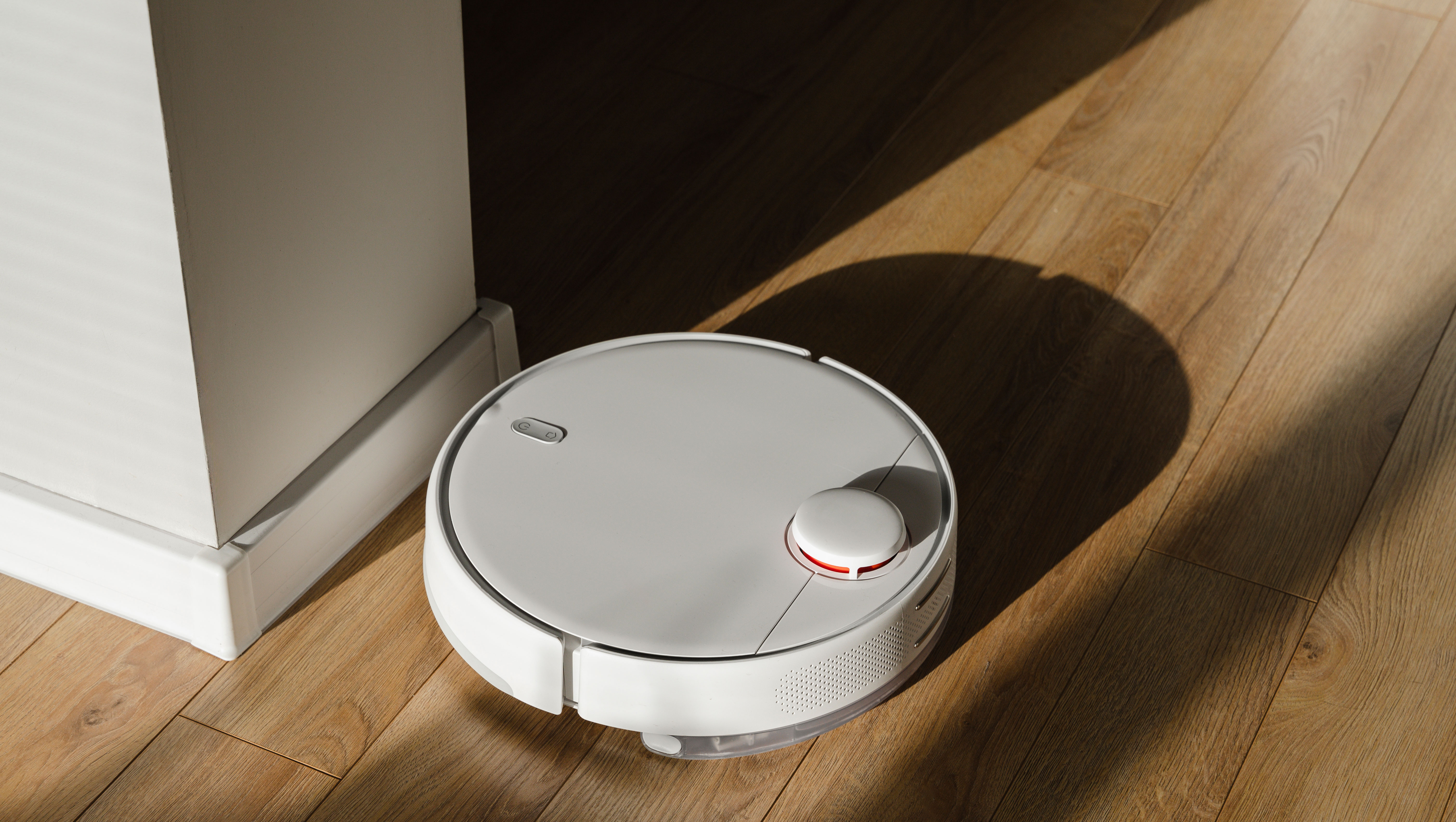 Robot vacuum cleaner on hardwood floor at home - stock photo