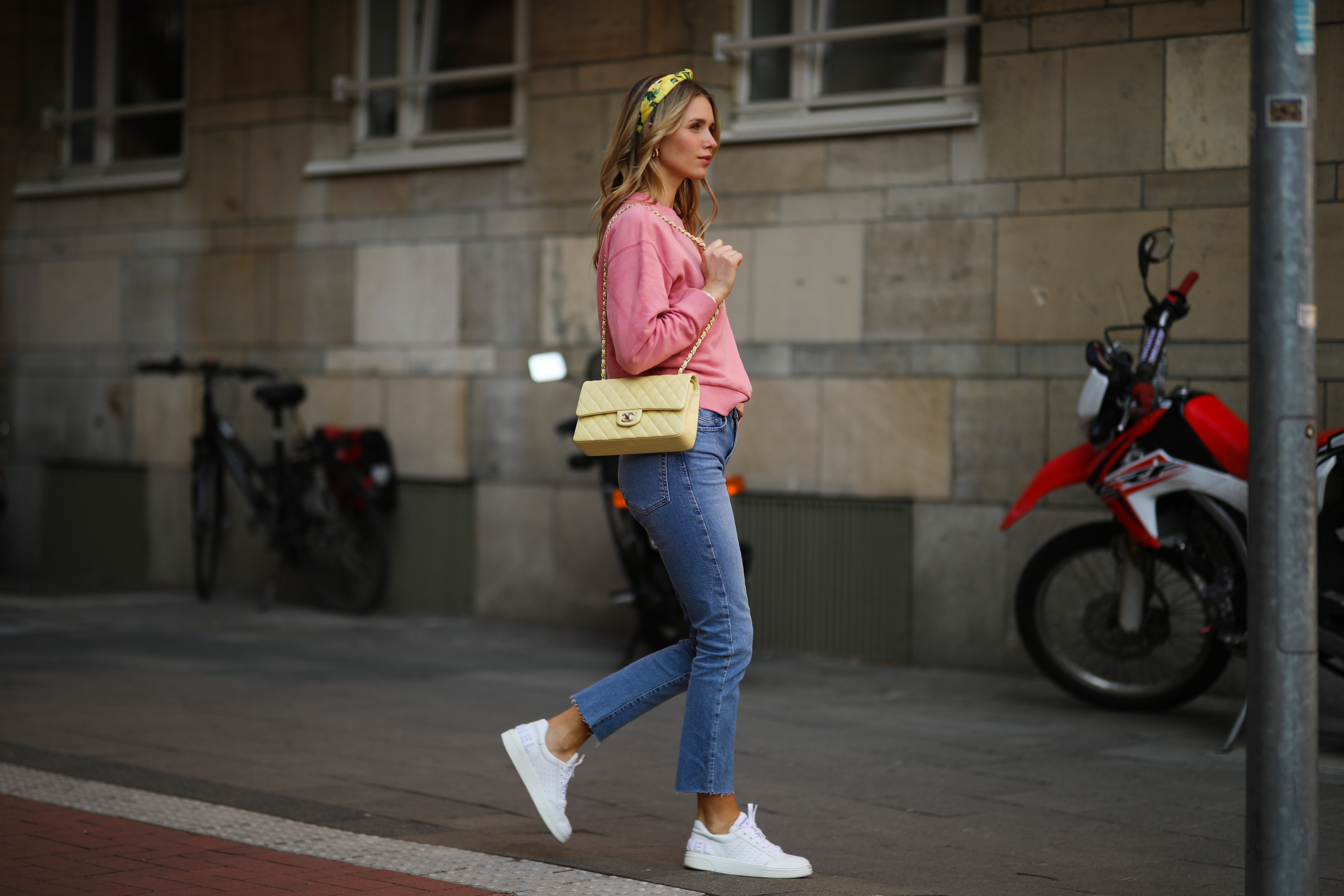 Scarlett Gartmann wearing pink Vogue sweater, Zara blue jeans, yellow H&M headband, yellow Chanel leather bag and white Chanel sneakers on March 24, 2021 in Dusseldorf, Germany.