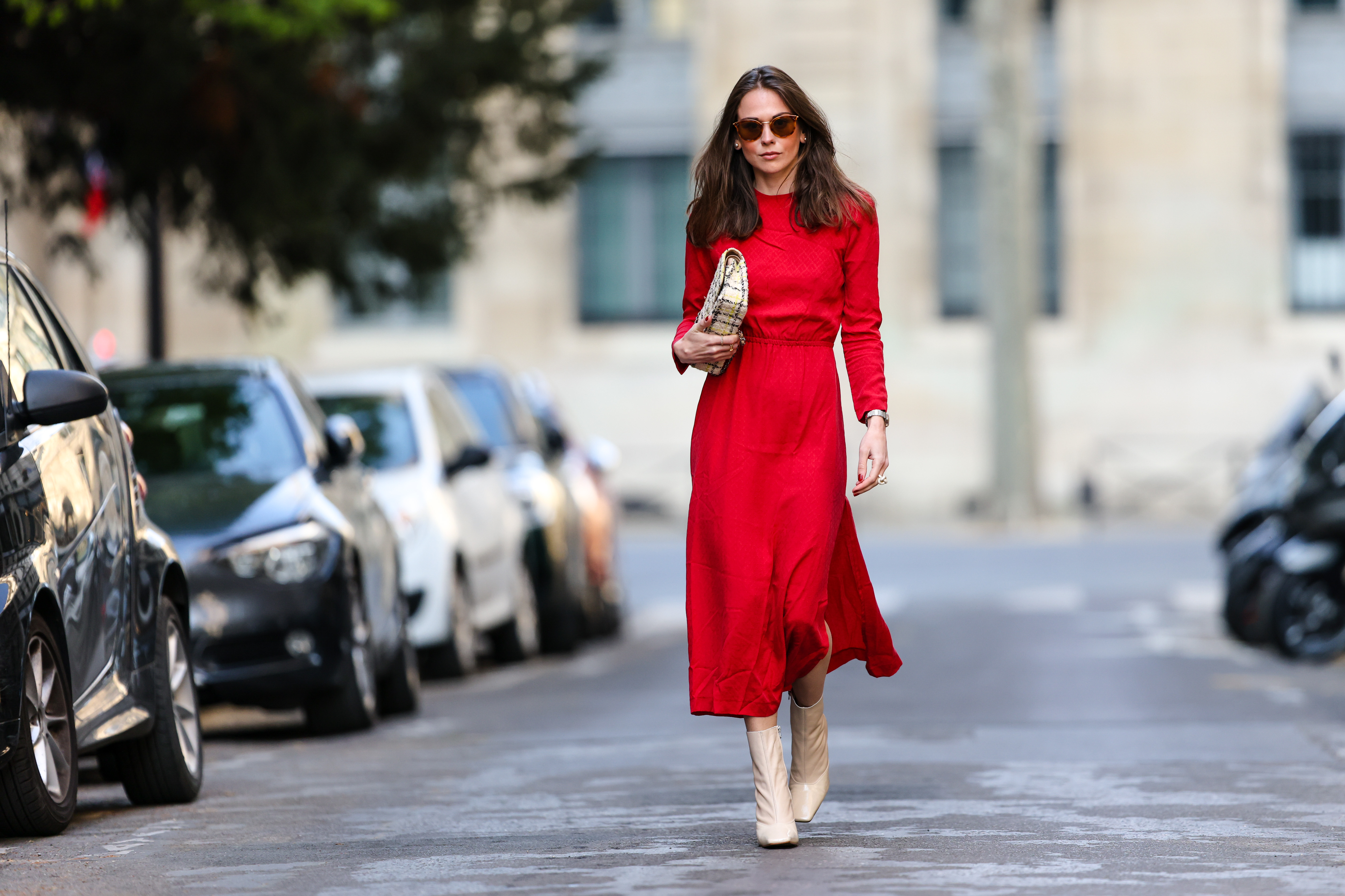PARIS, FRANCE - APRIL 08: Therese Hellström wears sunglasses, a red midi long dress with sleeves, a Chanel bag, beige square toe high heels shiny boots, on April 08, 2021 in Paris, France. (Photo by Edward Berthelot/Getty Images)
