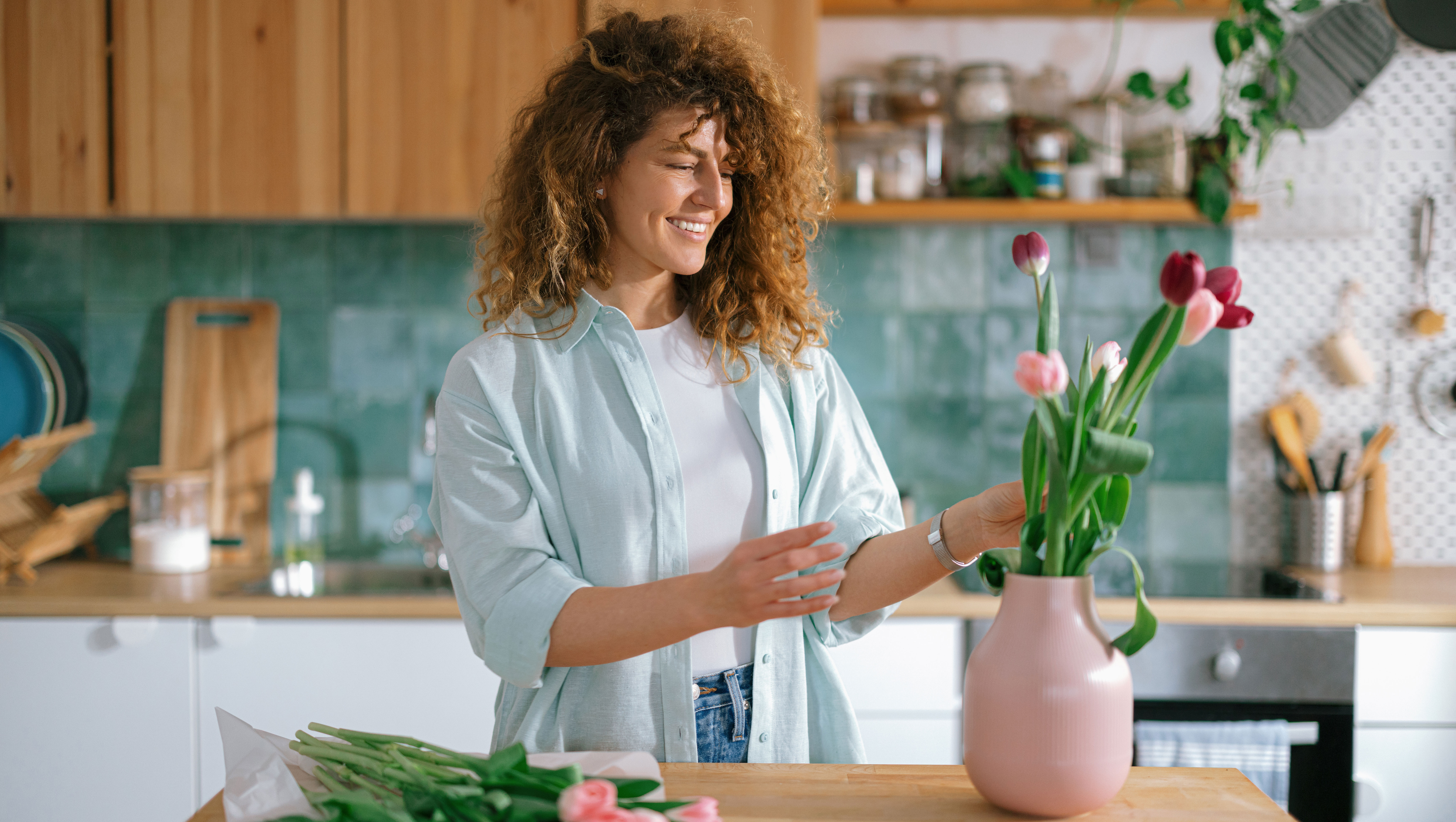 Happy woman enjoying while decorating her home with flowers.