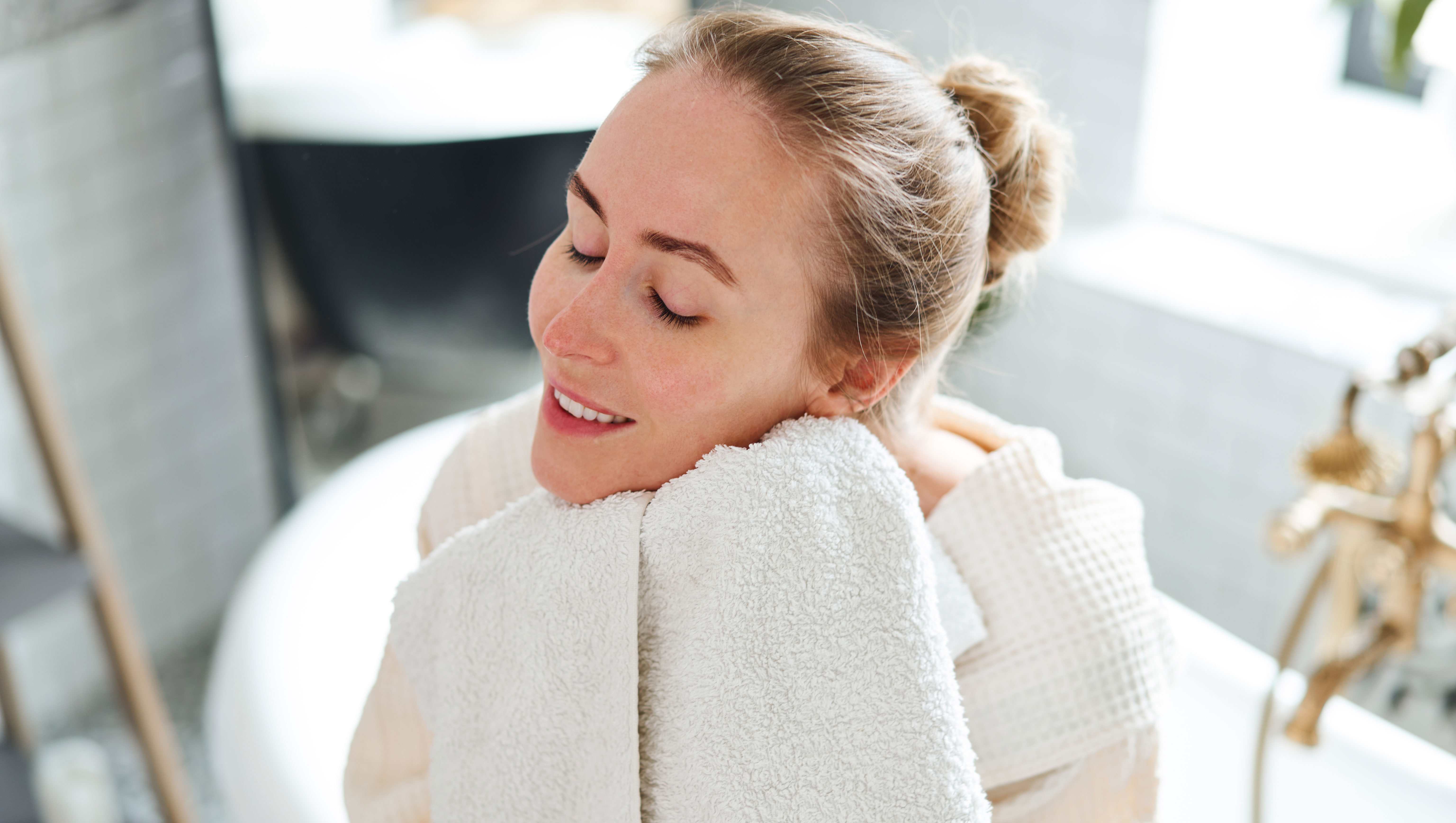Woman wiping face in bathroom - stock photo