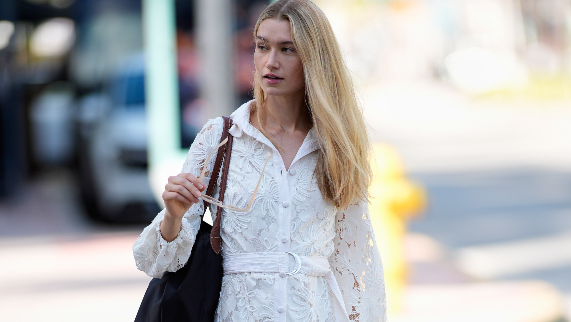 MIAMI, FLORIDA - OCTOBER 23: Maggie Krebs is seen wearing straight blonde hair, oversized light pink sunglasses, a Garota white lace long-sleeve belted mini dress, carrying a large black shoulder bag, and Dolce Vita beige knee-high boots outside Naeem Khan, during Miami Fashion Week on October 23, 2025 in Miami, Florida. (Photo by 305pics/Getty Images)