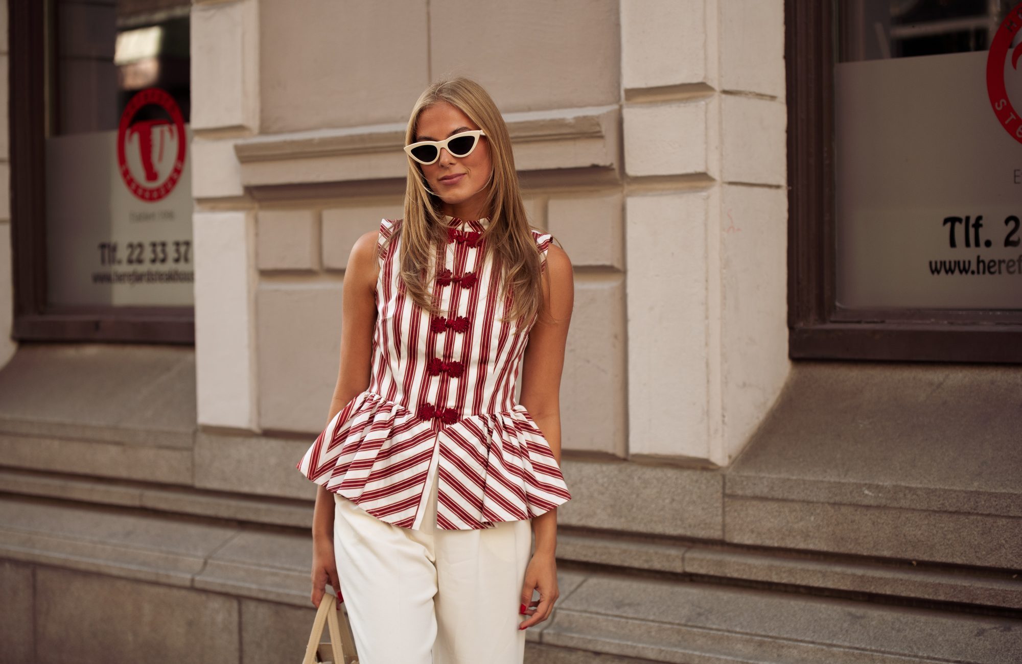 OSLO, NORWAY - AUGUST 26: Martine Akersveen wears white pants, red and white striped top and a beige bag outside the Christian Aks show during Oslo Fashion Week on August 26, 2025 in Oslo, Norway. (Photo by Raimonda Kulikauskiene/Getty Images)