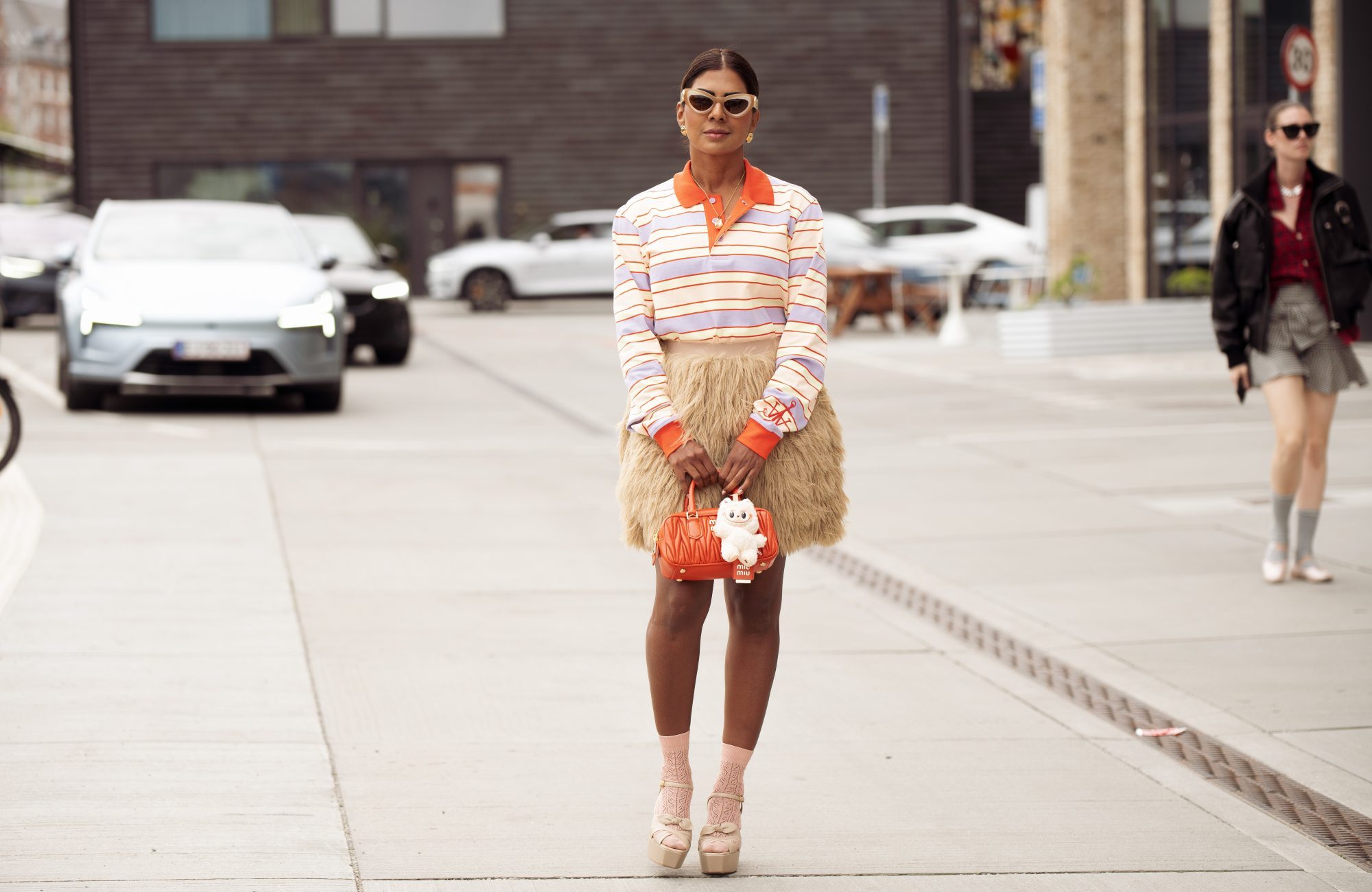 COPENHAGEN, DENMARK - AUGUST 07: Zufi Alexander wears beige mini skirt made of fur, orange MiuMiu bag with beige Labubu charm, purple, yellow and orange stripped long sleeve top, light pink socks, beige platform shoes during Copenhagen Fashion Week day four on August 07, 2025 in Copenhagen, Denmark. (Photo by Raimonda Kulikauskiene/Getty Images)