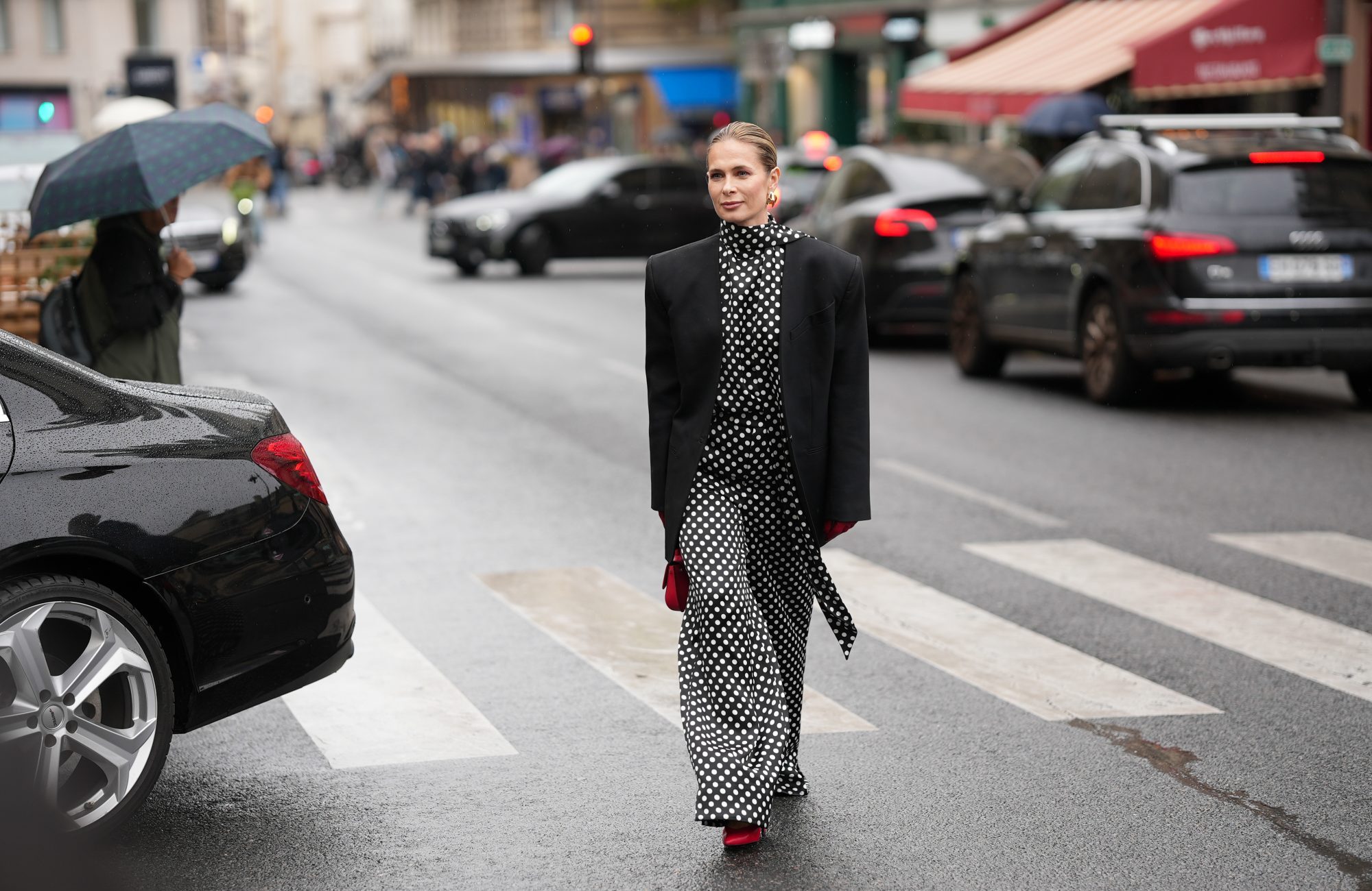 PARIS, FRANCE - OCTOBER 3: Iryna Thater is seen wearing full Nina Ricci look; a black oversized blazer jacket; a black and white polka dot high-neck blouse; a matching wide- leg polka dot trousers; red leather pointed-toe pumps shoes; gold-tone sculptural hoop earrings; red leather gloves; a red leather mini top-handle bag her blonde hair is styled a slicked-back pulled into a low bun outside the Nina Ricci Show during the Womenswear Spring Summer 2026 as part of Paris Fashion Week on October 3, 2025 in Paris, France. (Photo by Moritz Scholz/Getty Images)