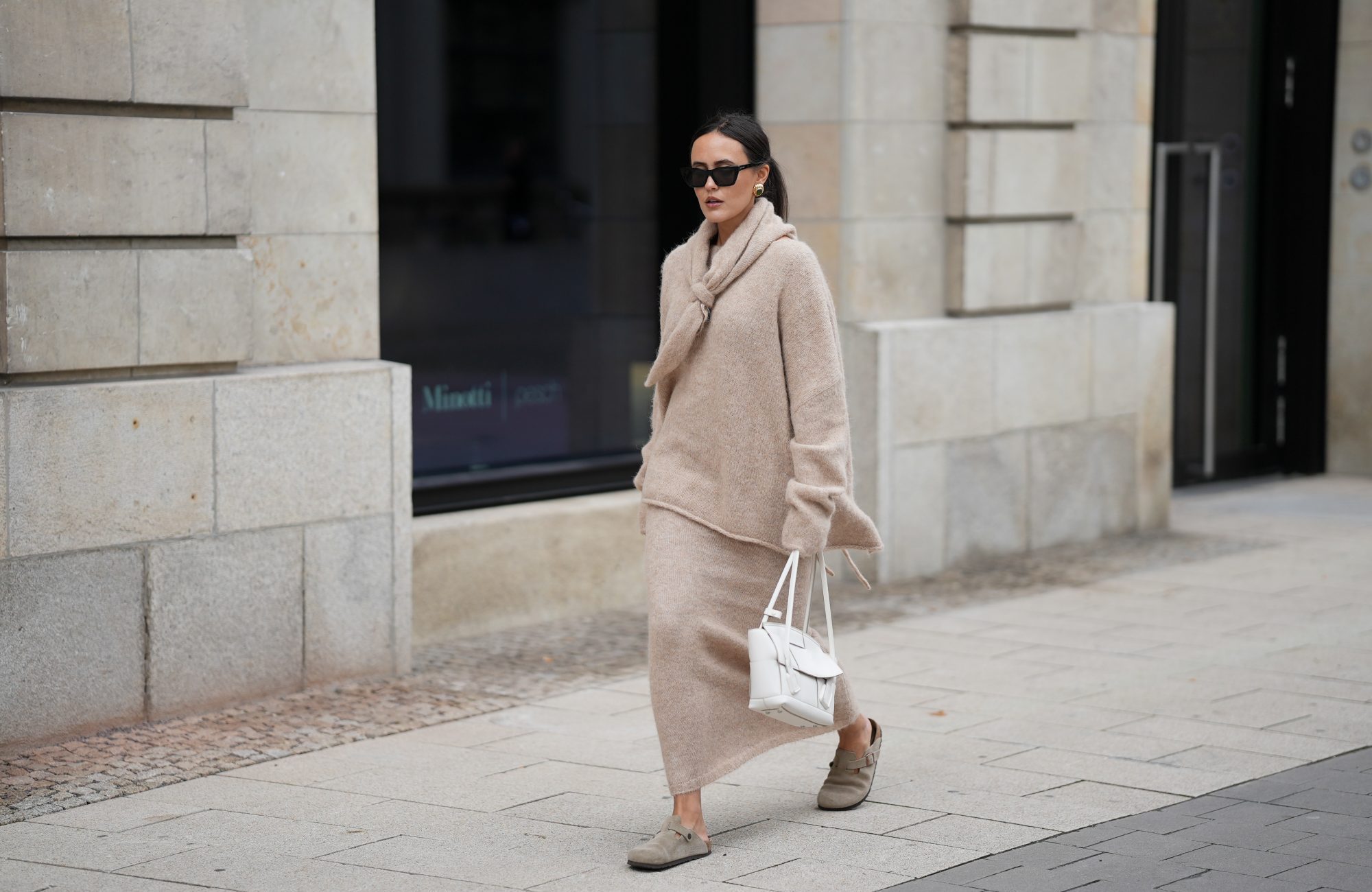 HAMBURG, GERMANY - OCTOBER 16: Laura Noltemeyer is seen wearing an oversized beige alpaca wool sweater with tie-back detailing by Aylin K&ouml;nig; a long alpaca wool knit skirt in a straight cut by Aylin K&ouml;nig; an alpaca knit scarf draped and knotted around the neck by Aylin K&ouml;nig; beige suede Boston clogs by Birkenstock; a white intrecciato leather handbag called &bdquo;Arco Bag&ldquo; by Bottega Veneta; slim black cat-eye sunglasses by Yves Saint Laurent; gold statement earrings with a green stone detail by Mango; her brown and straight hair is tied in a low ponytail on October 16, 2025 in Hamburg, Germany. (Photo by Moritz Scholz/Getty Images)