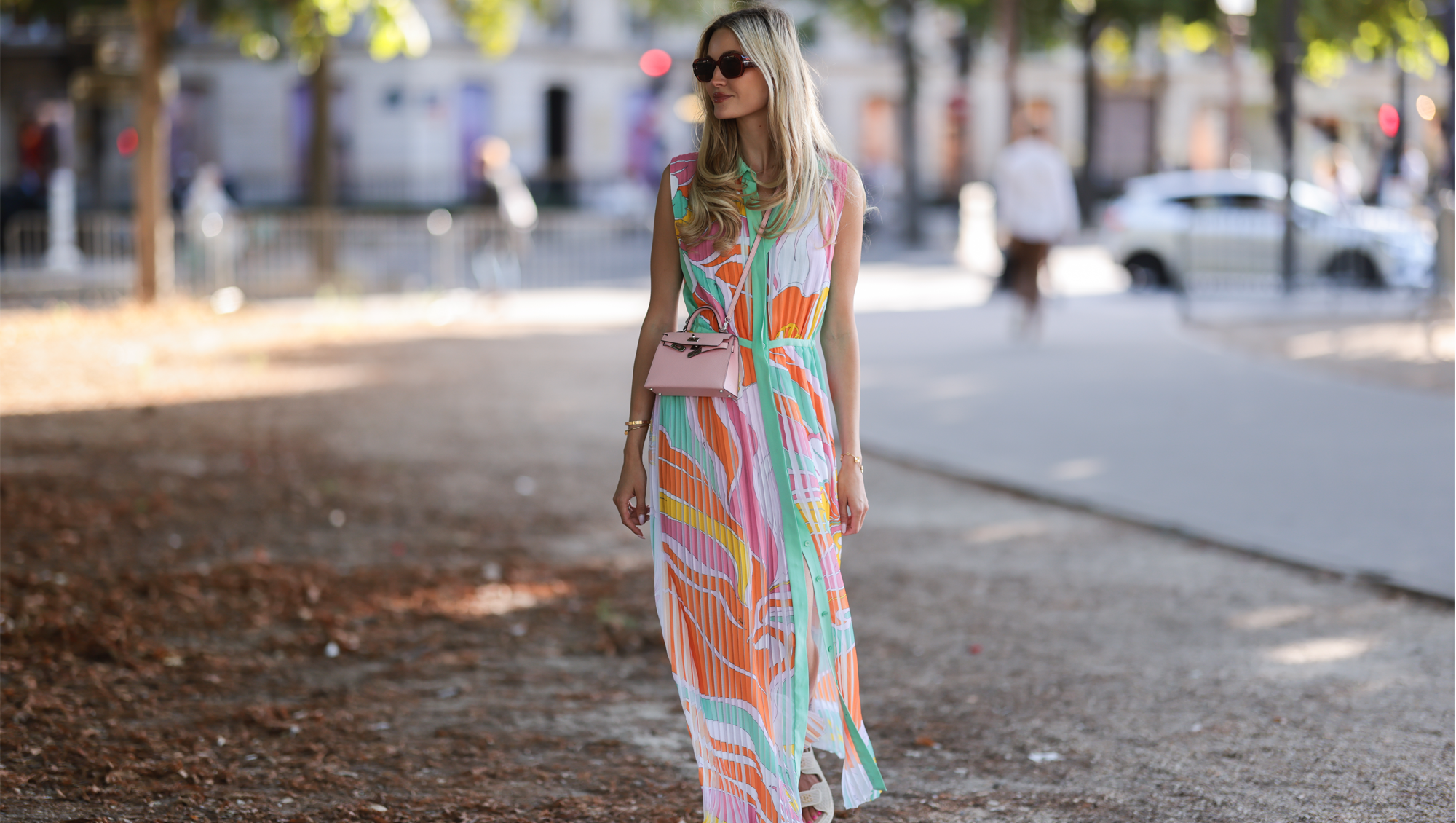 Mandy Bork seen wearing brown sunglasses from Tom Ford, a colorful buttoned / pleated / sleeveless long dress from Emilio Pucci, a pale pink Hermes Kelly mini bag and white creme sandals from Chanel, during Paris Fashion Week - Haute Couture Fall Winter 2022 2023, on July 06, 2022 in Paris, France.