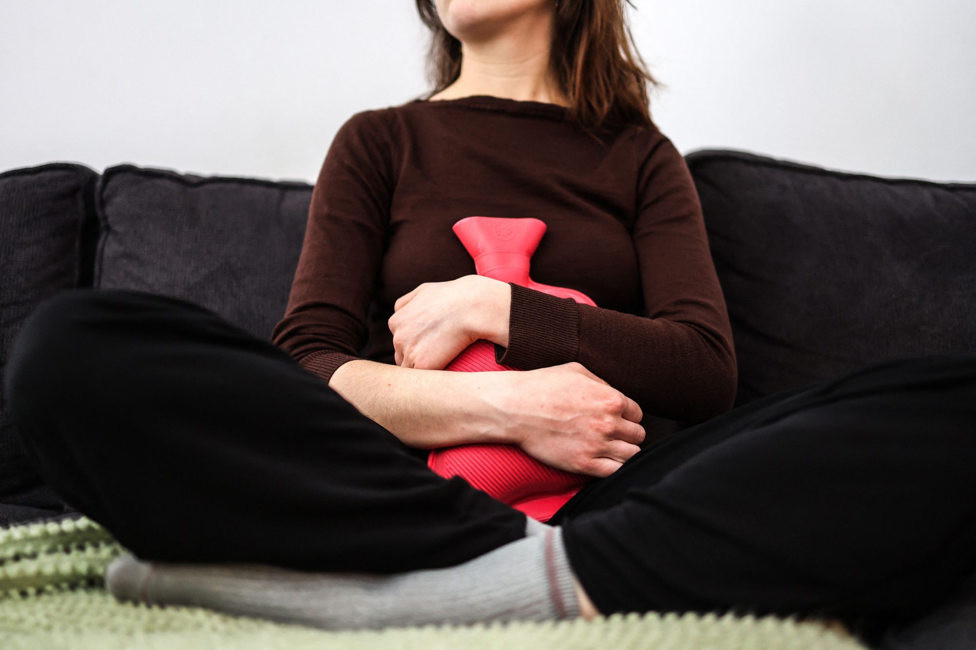 Getty Images 1247581156 - Woman with a heating pad on her abdomen