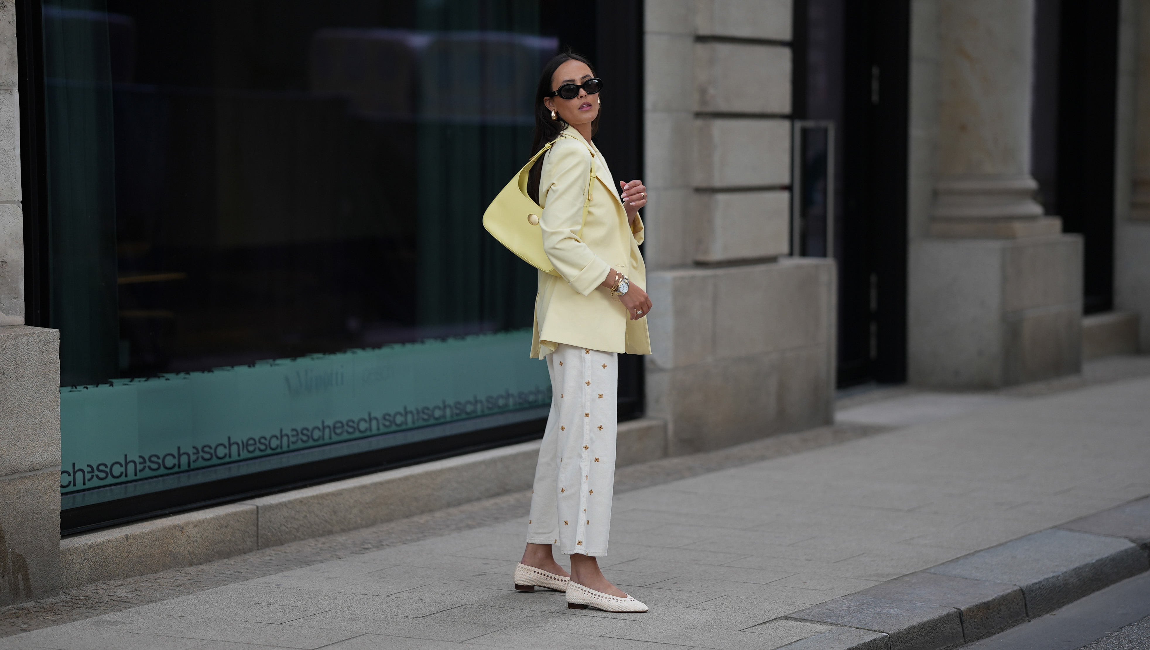 HAMBURG, GERMANY - MAY 5: Laura Noltemeyer is seen wearing a butter yellow blazer from Zara, a 5-pocket wide-leg jeans with all-over small flower embroidery in ecru from Sézane x Lucia Vergara, natural woven raffia Anya low ballerinas in ecru from Sézane, a pale yellow shoulder bag with small golden details from Marc Cain, black TRIOMPHE sunglasses with round glasses and golden logo detail on temples from Celine, golden drop earrings, golden Love bracelets from Cartier, stacked rings from Cartier, small silver-golden Datejust watch from Rolex on May 5, 2025 in Hamburg, Germany. (Photo by Moritz Scholz/Getty Images)