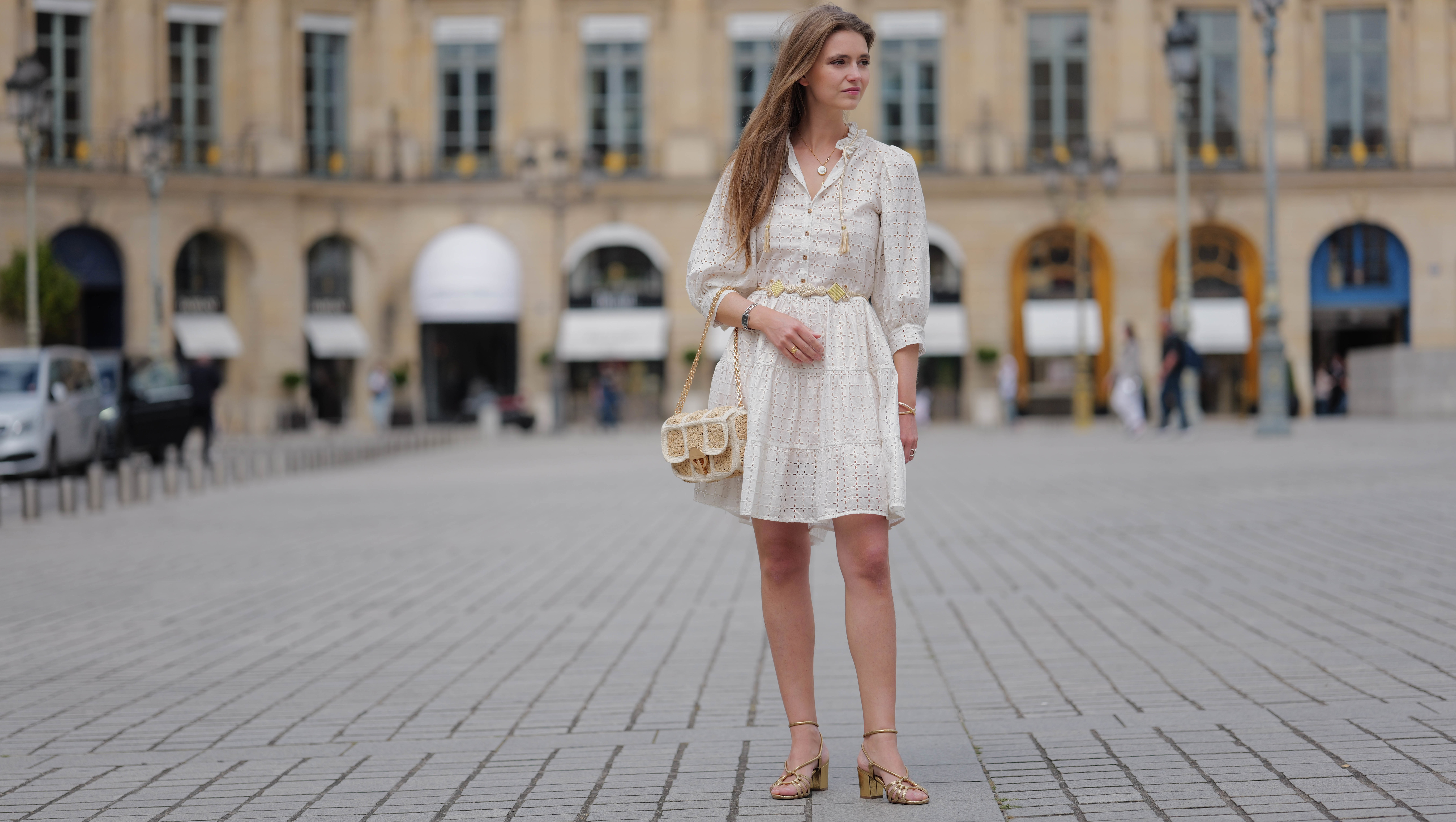 PARIS, FRANCE - JUNE 14: Segolene Hyppolite wears sunglasses, a white mini pleated and gathered summer dress with floral embroidery and long sleeves from Anne Fontaine, a rope belt from Anne Fontaine, a raffia bag from Vanessa Bruno, golden sandals / shoes from Sezane, during a street style fashion photo session, on June 14, 2024 in Paris, France. (Photo by Edward Berthelot/Getty Images)