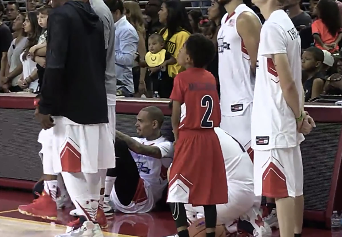 Chris Brown sits during the national anthem